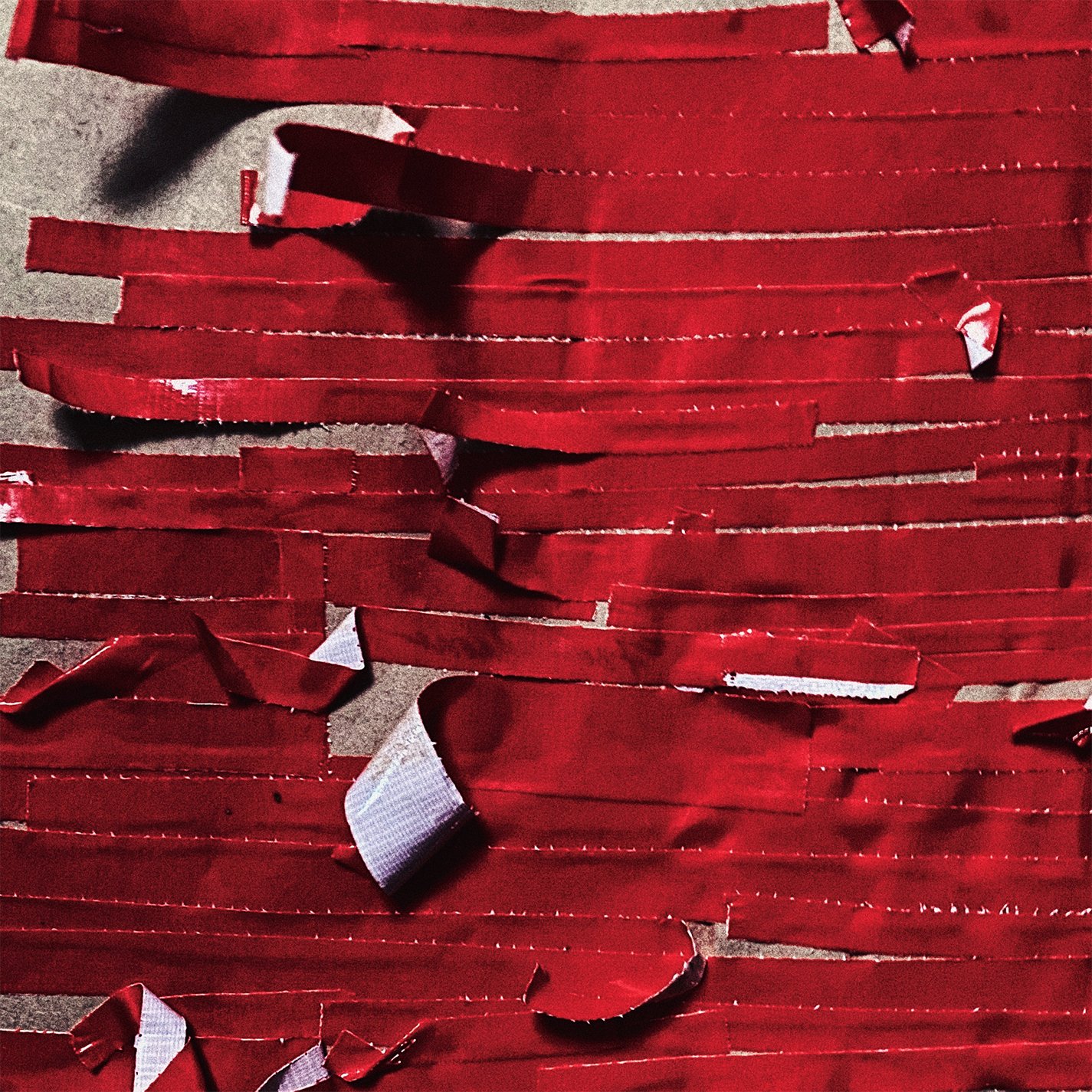Red paper strips and torn pieces scattered on a surface.