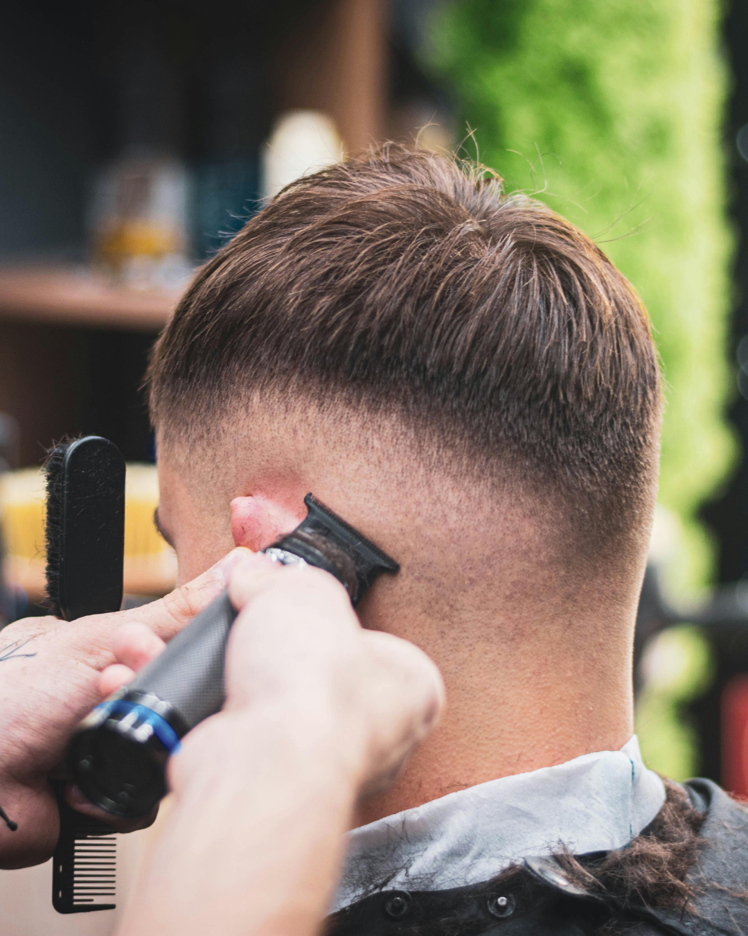 Barber shaving a man's head with clippers in a barbershop.