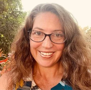 female client smiling with glasses and long curly brown hair