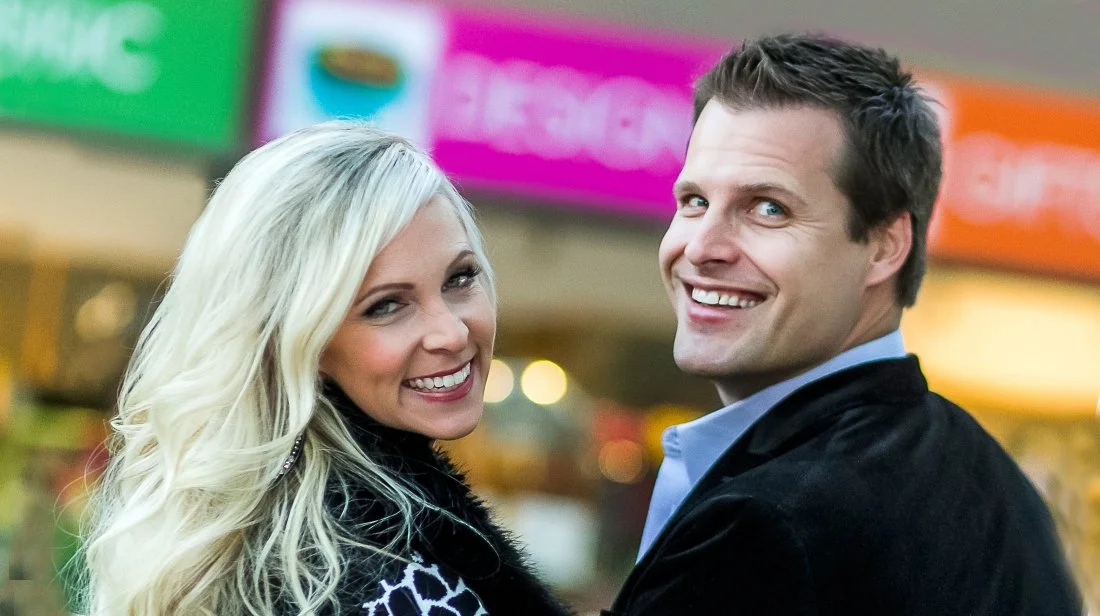 A smiling couple standing close together in a shopping mall
