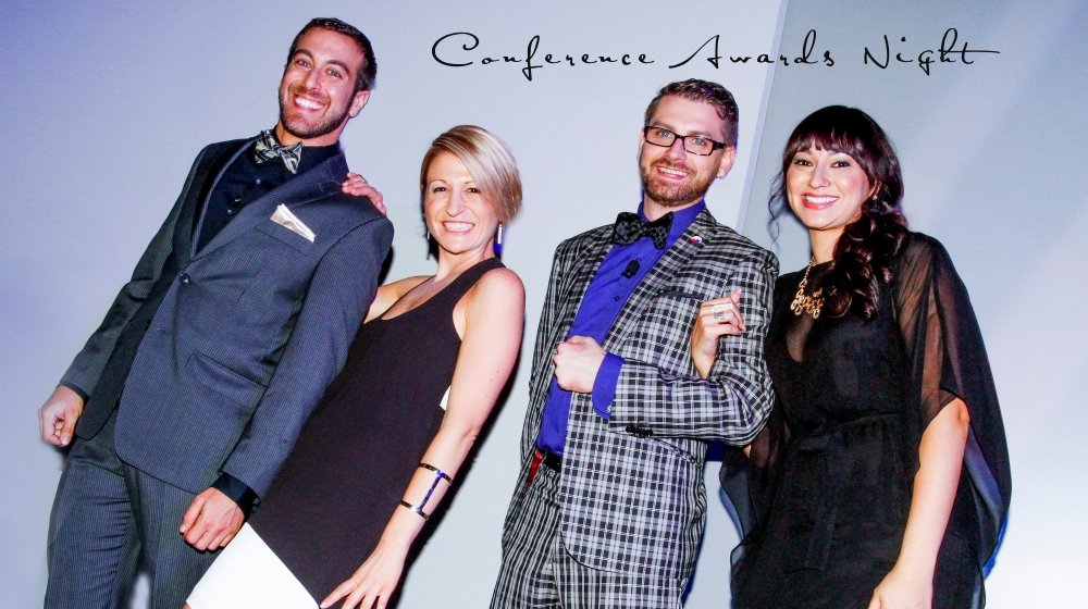Four well-dressed people standing together at a conference awards night, smiling for the camera.