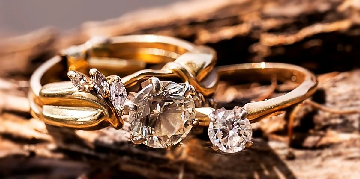 Close-up of gold rings with diamonds on a wooden surface.