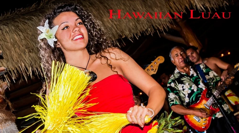 Hawaiian luau with a woman in a red dress and a flower in her hair, holding yellow tiki torches, and a man playing guitar in the background under a thatched roof.
