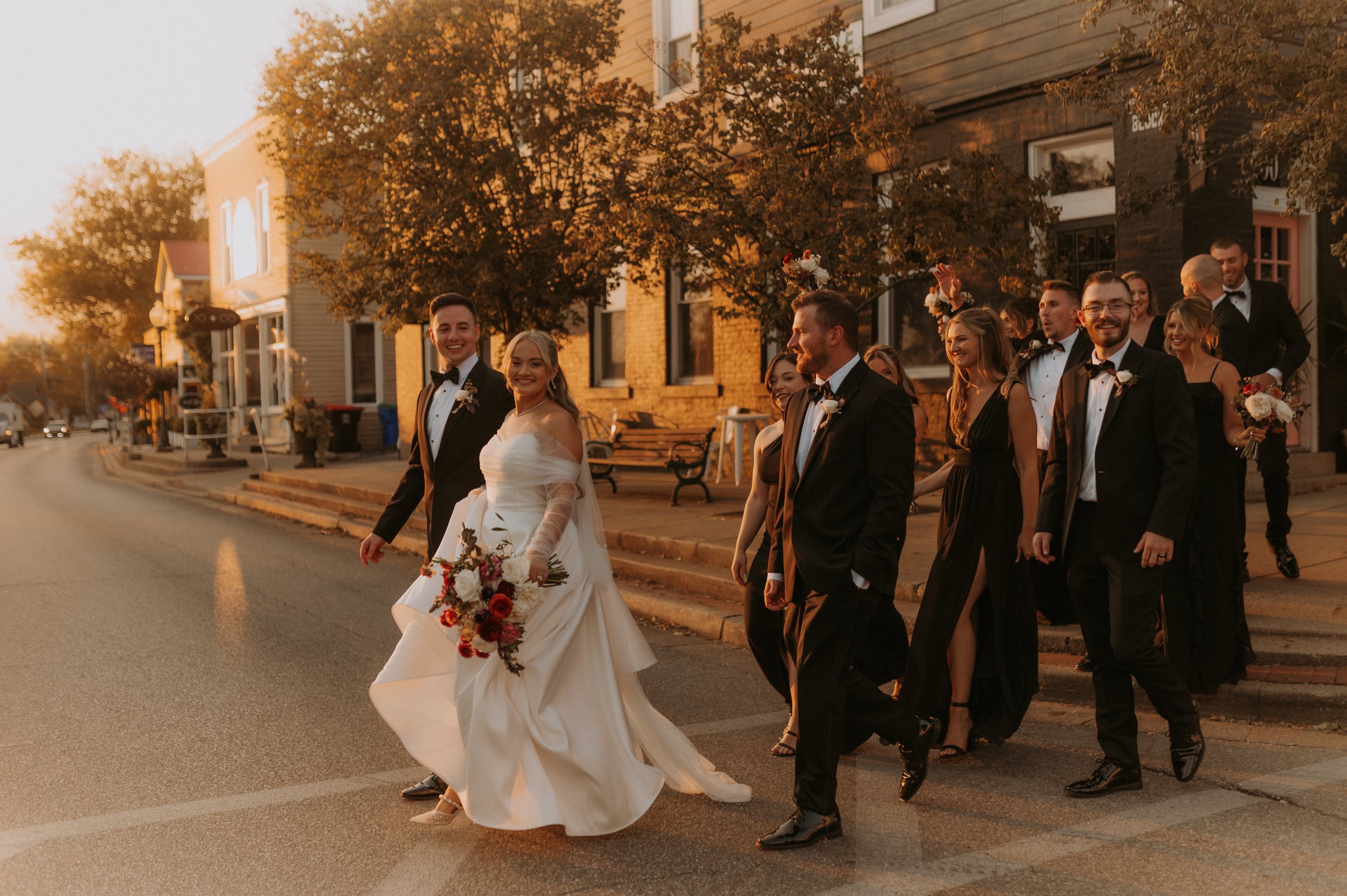 Black and white photo of a person carrying another person wearing a dress and heels on a street.