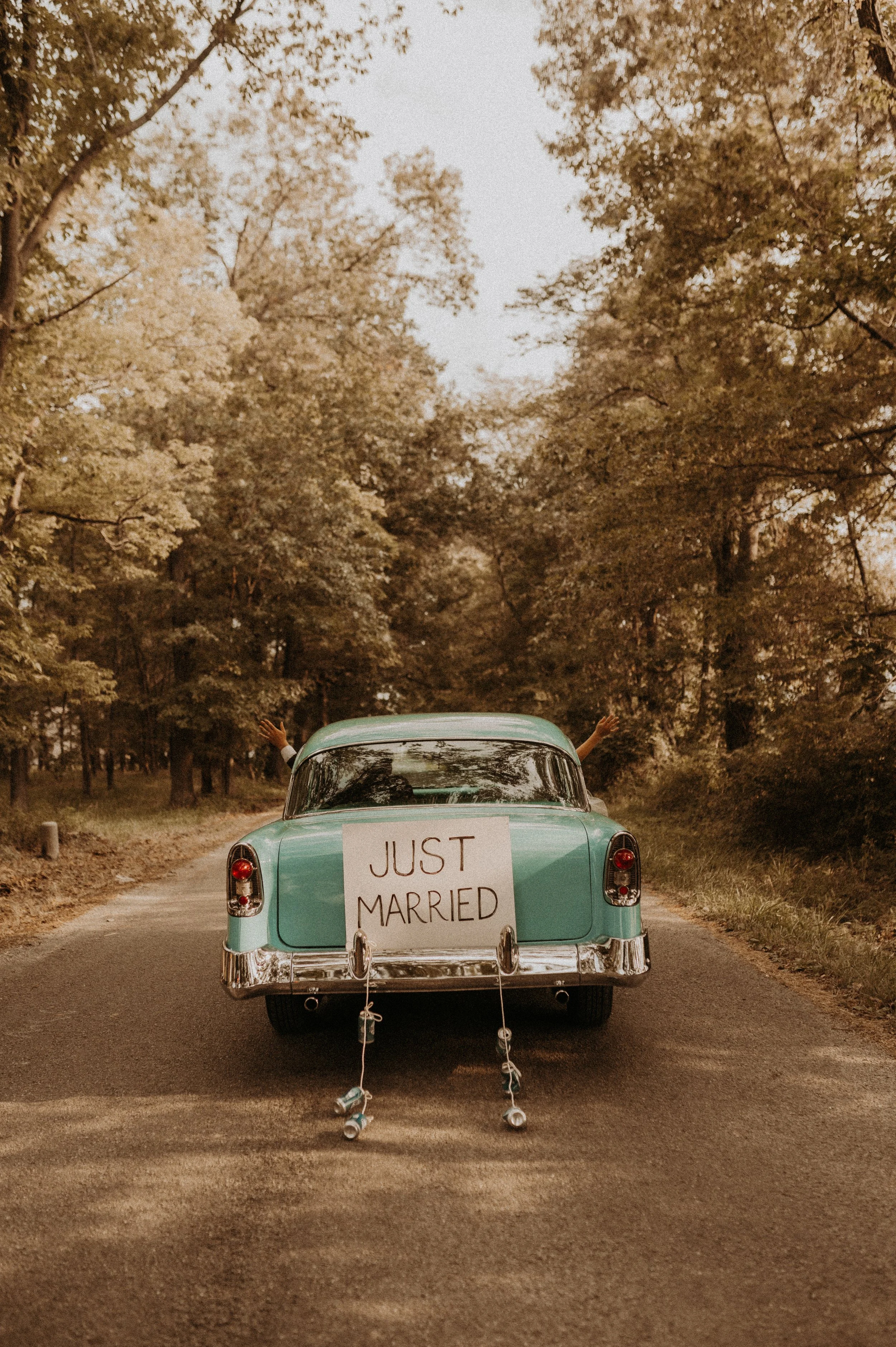 Black and white photo of a couple holding hands, with the woman in a flowing dress and the man in a suit, walking on a grassy field.