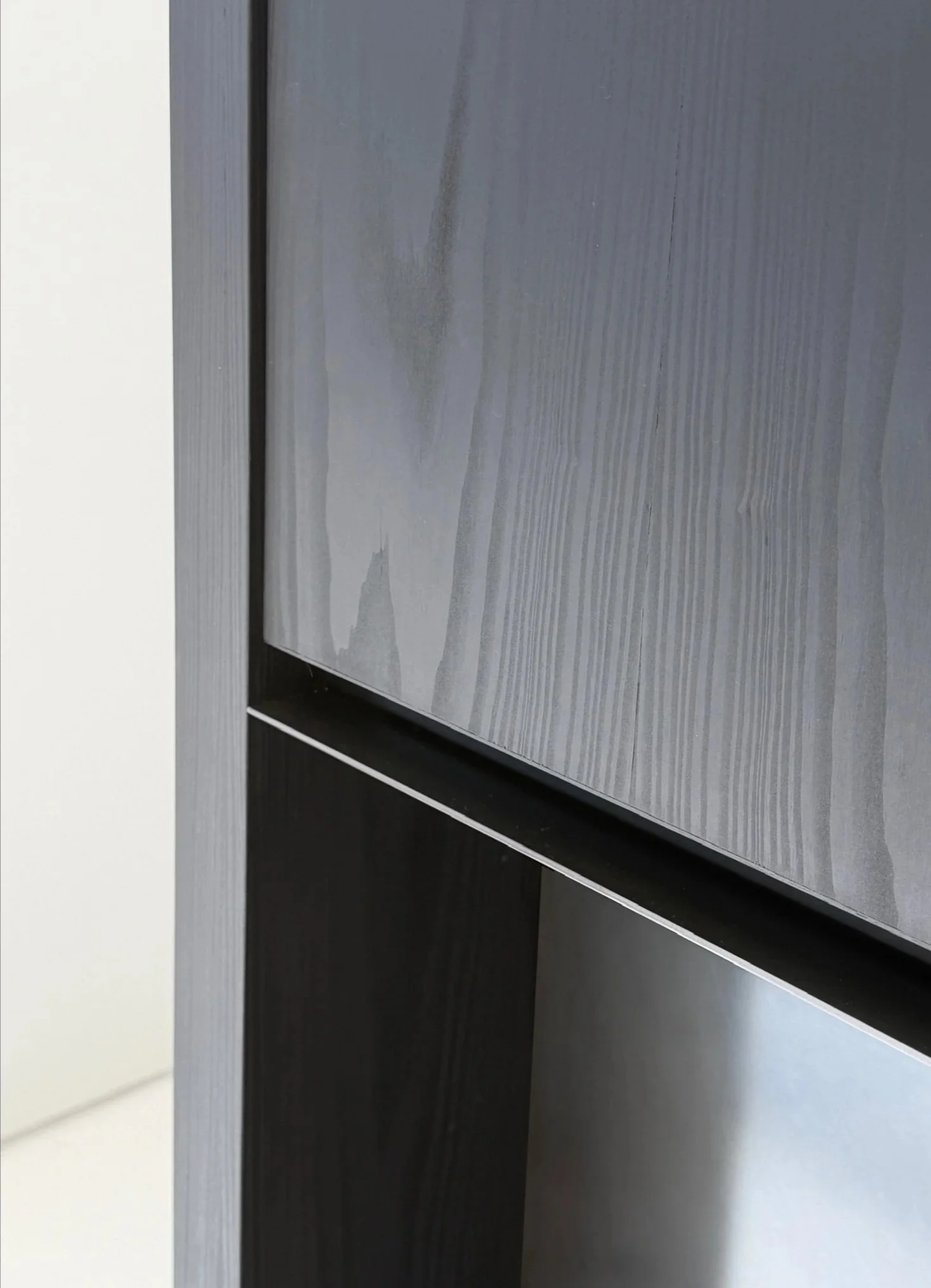 Close-up interior detail highlighting the material contrast between blackened oak wood grain and a sleek raw steel fireplace surround.