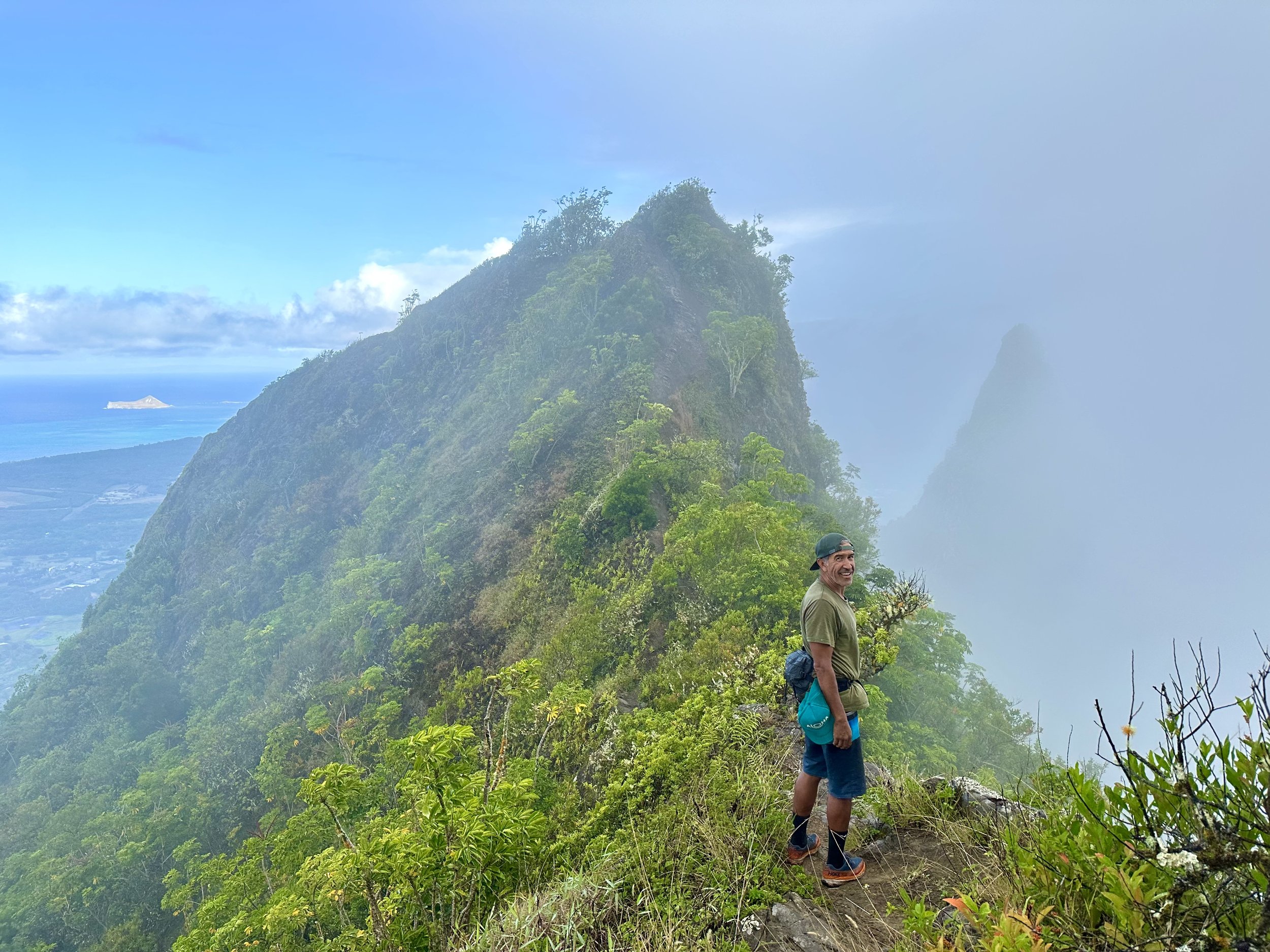 A hiker is stopped on a misty mountain trail in Hawaii.