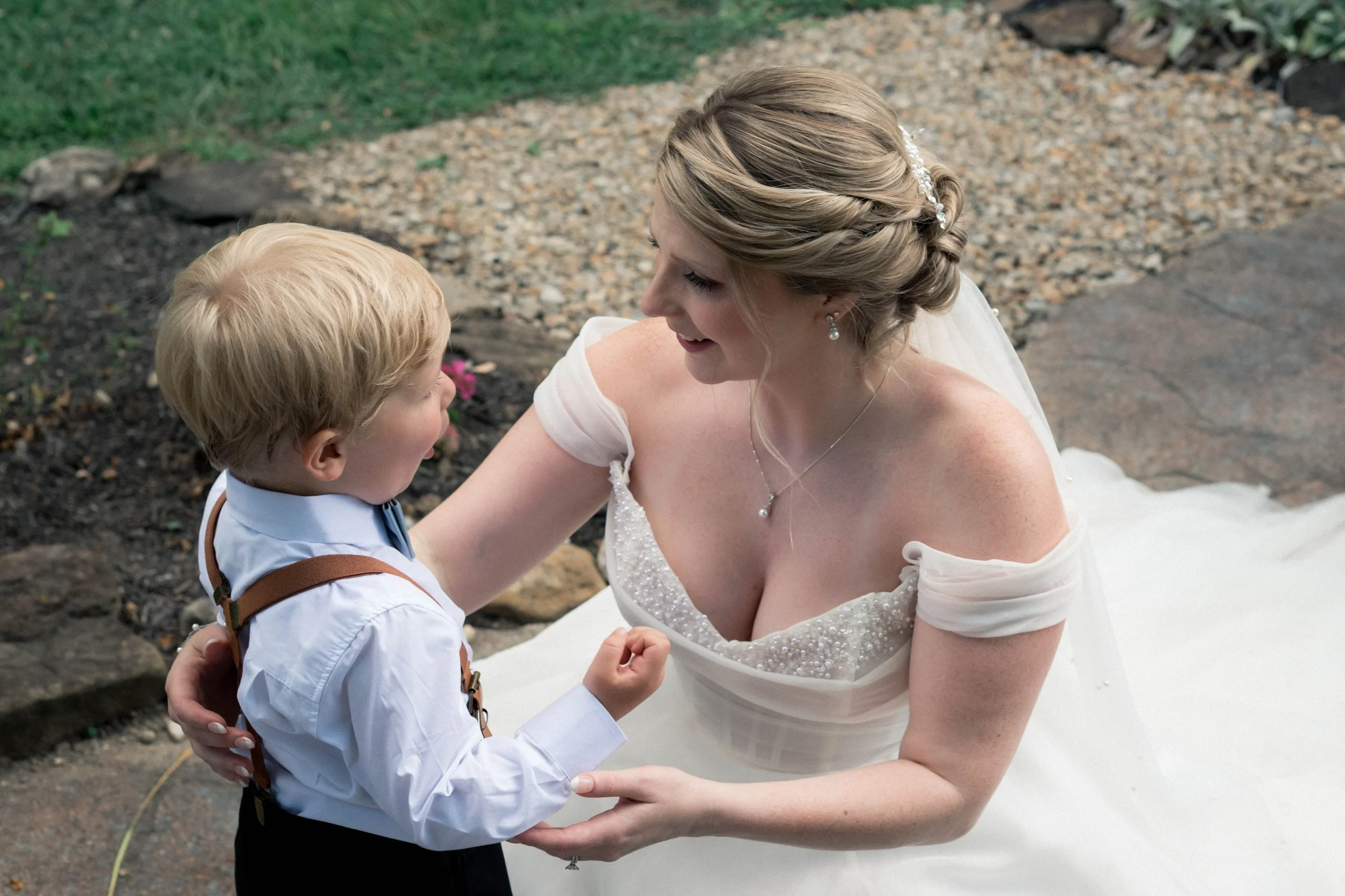 A candid moment of a bride embracing a child on her wedding day.