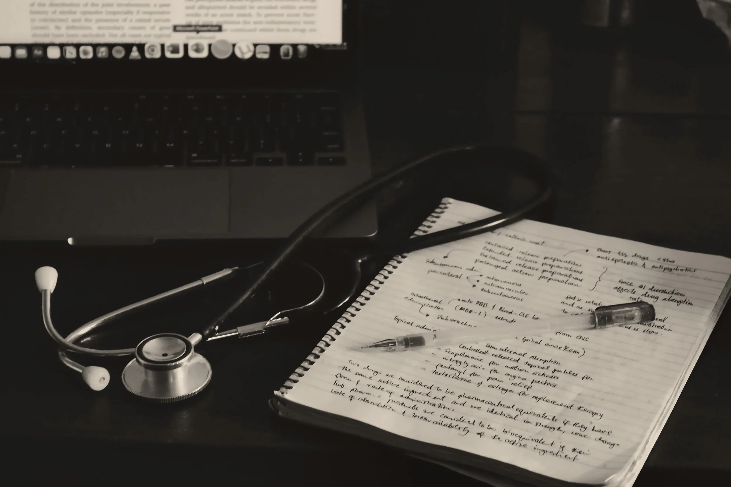 A desk with a laptop, stethoscope, notebook with handwritten notes, and a pen – Nordica Scientific