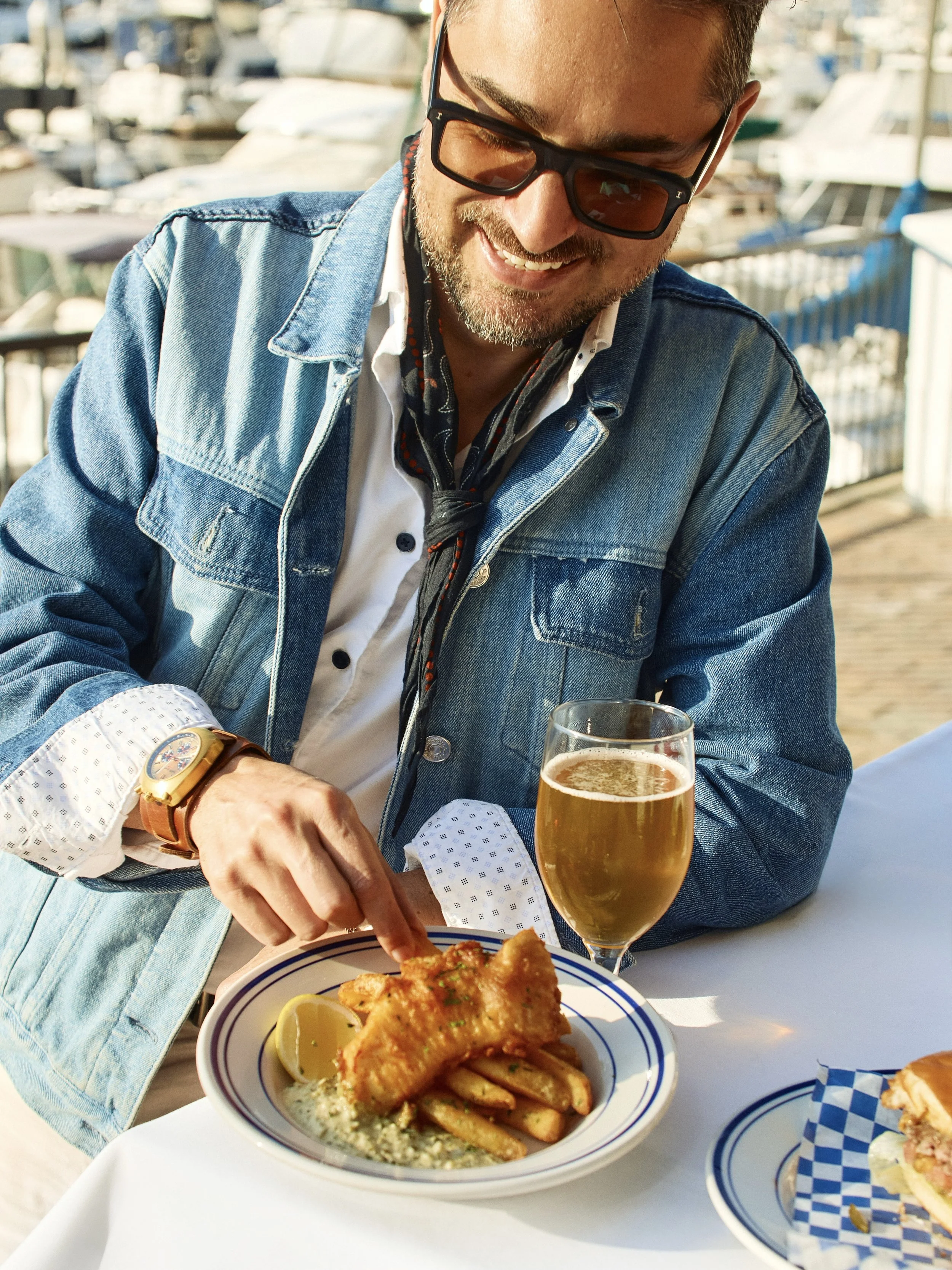 man enjoying fish n chips and beer overlooking the marina on the patio