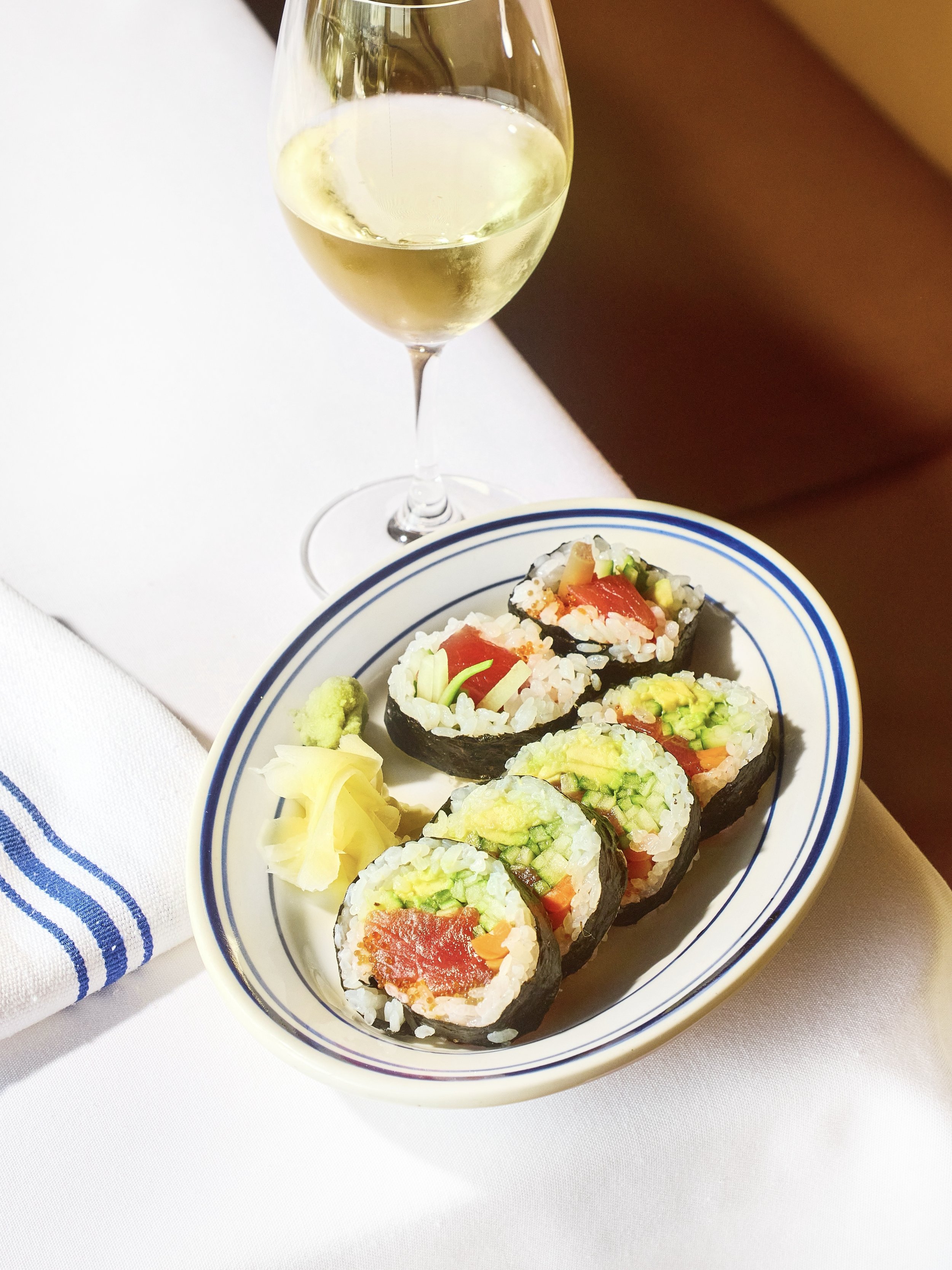 sushi rolls and glass of white wine