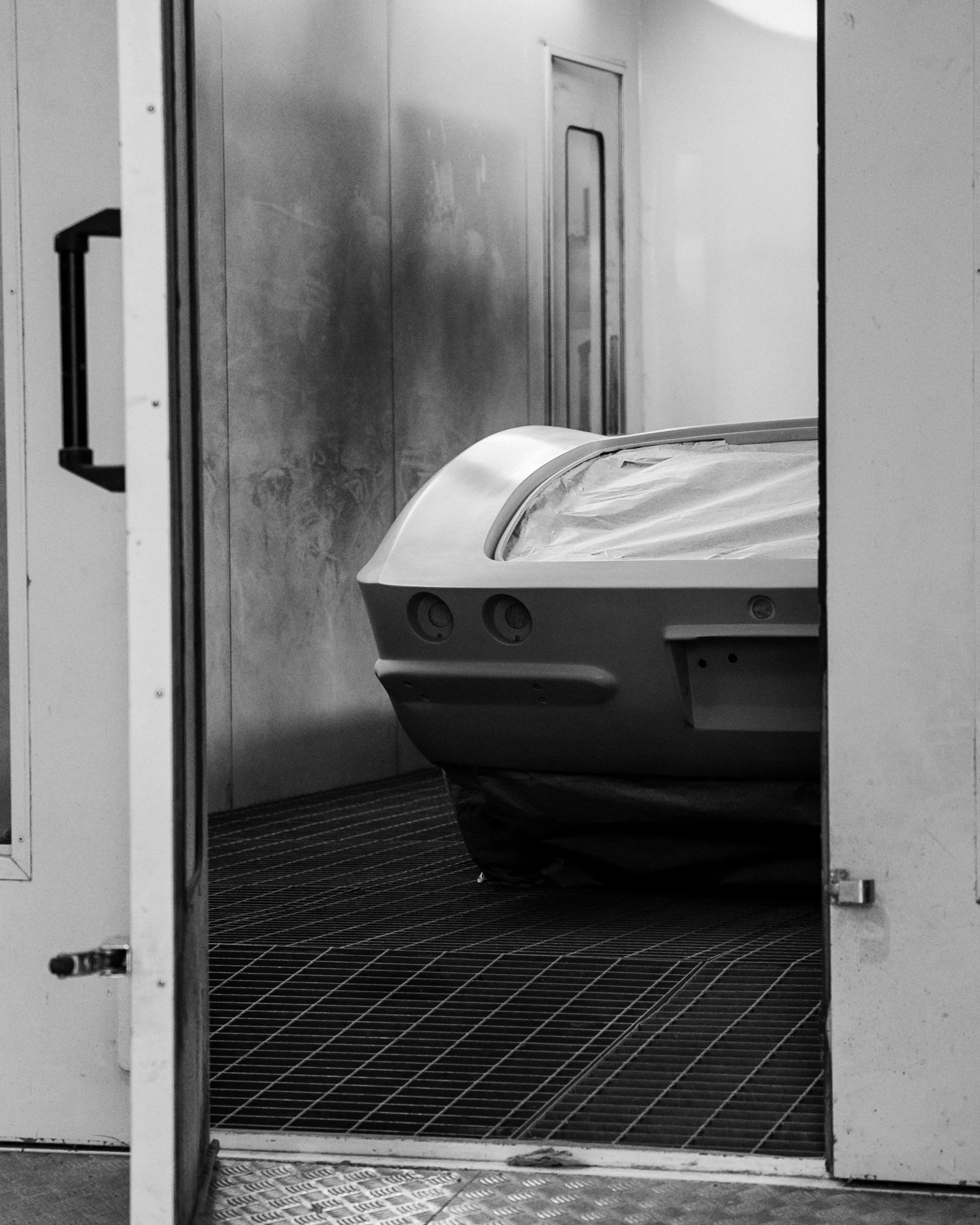Corvette in paint booth undergoing bodywork restoration