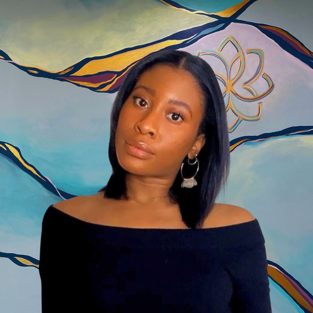 A woman with glasses and twisted hair smiles at the camera, standing in front of a colorful mural with a floral design and abstract patterns.