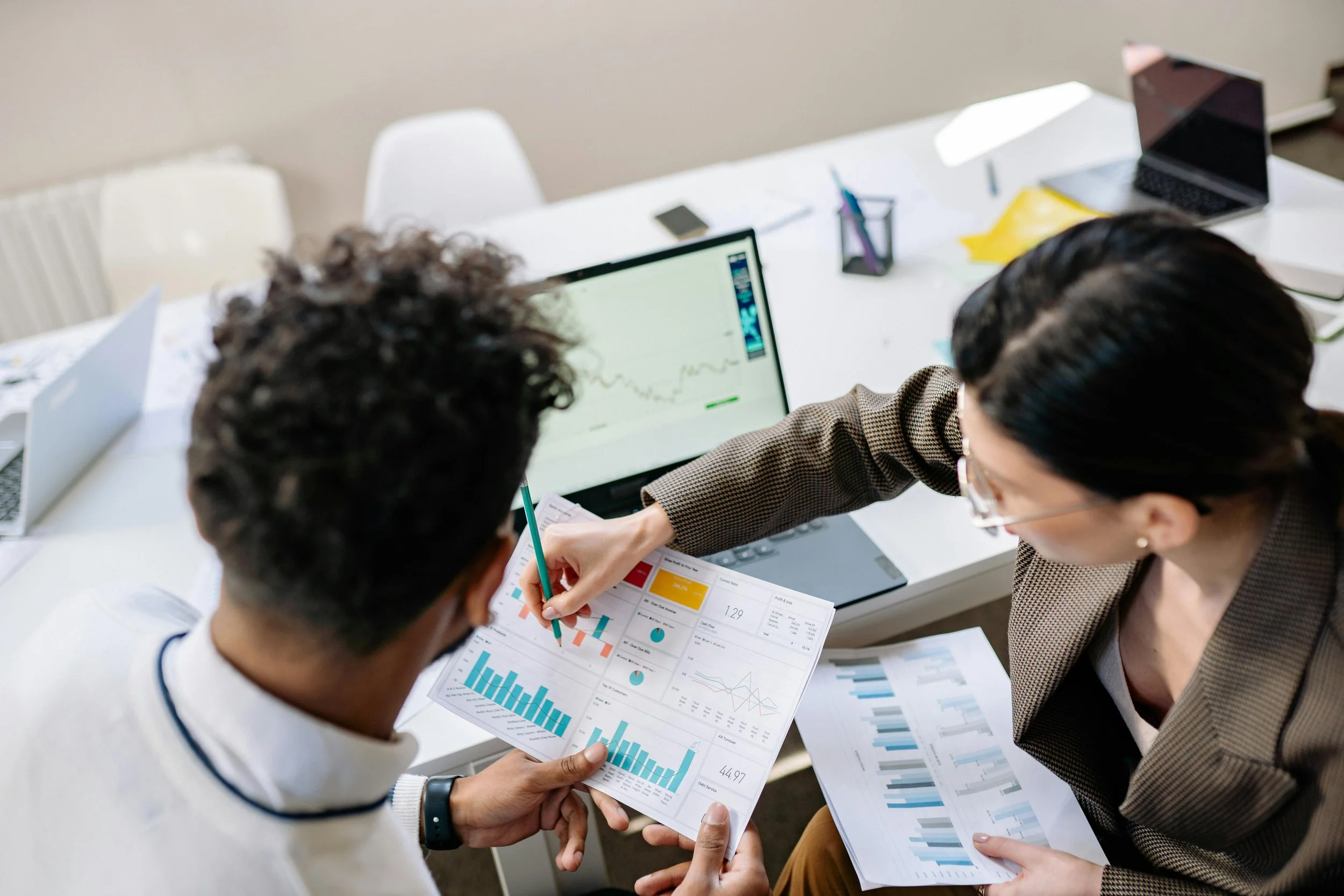 Two professionals reviewing business reports and graphs in an office meeting.