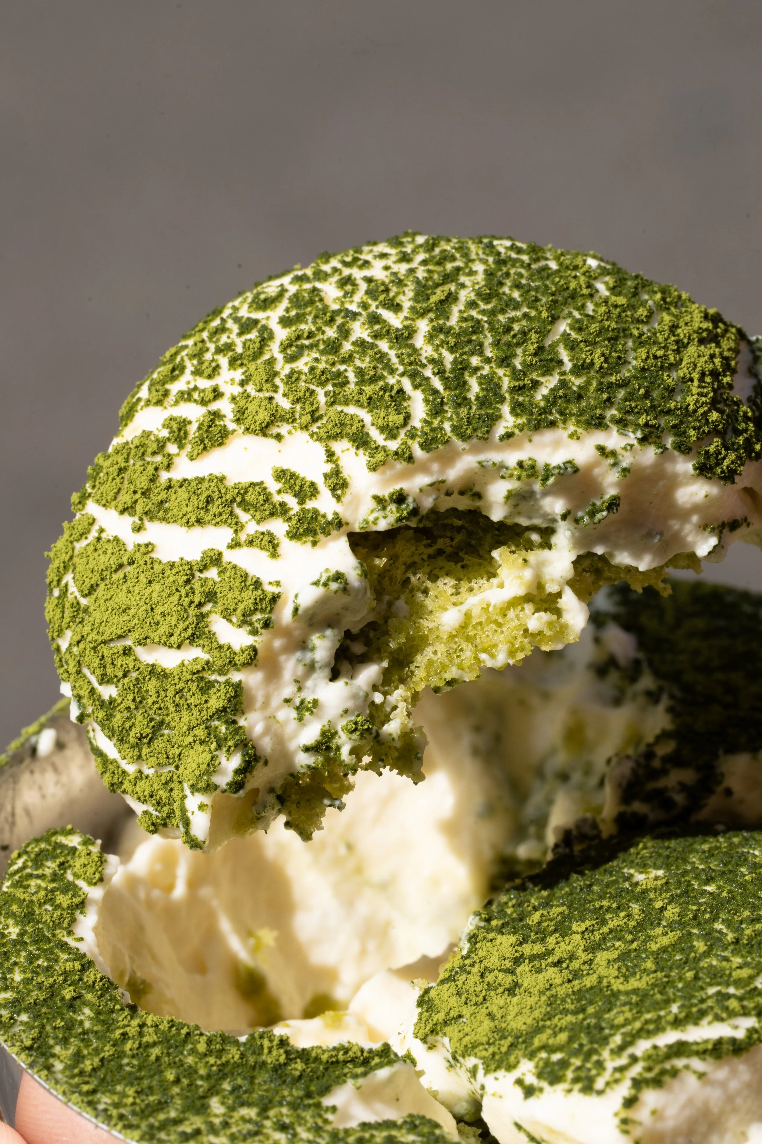 Close-up of matcha tiramisu bite with a creamy texture and green powder topping.