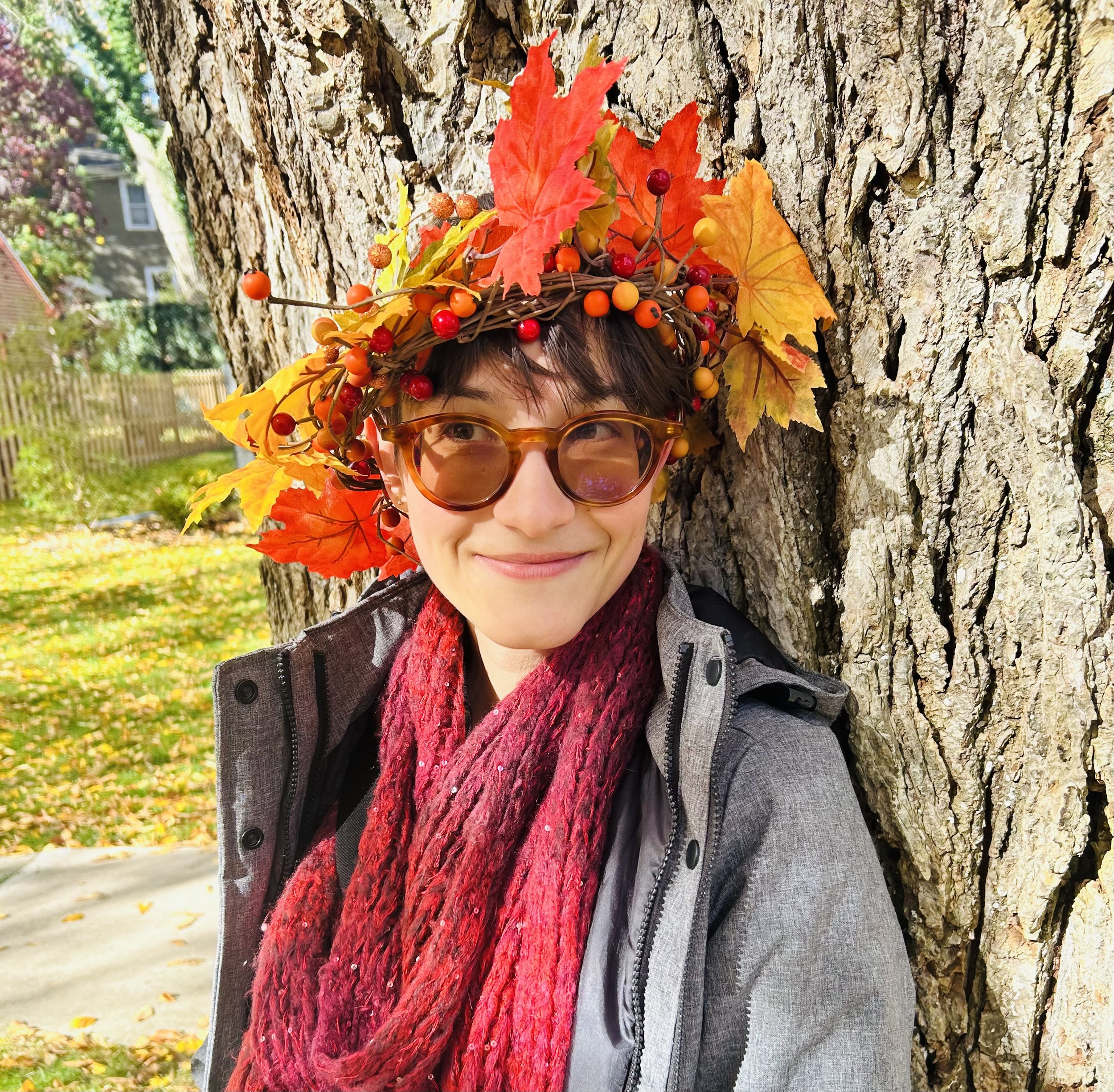 Cam wears a crown of leaves in front of a tree