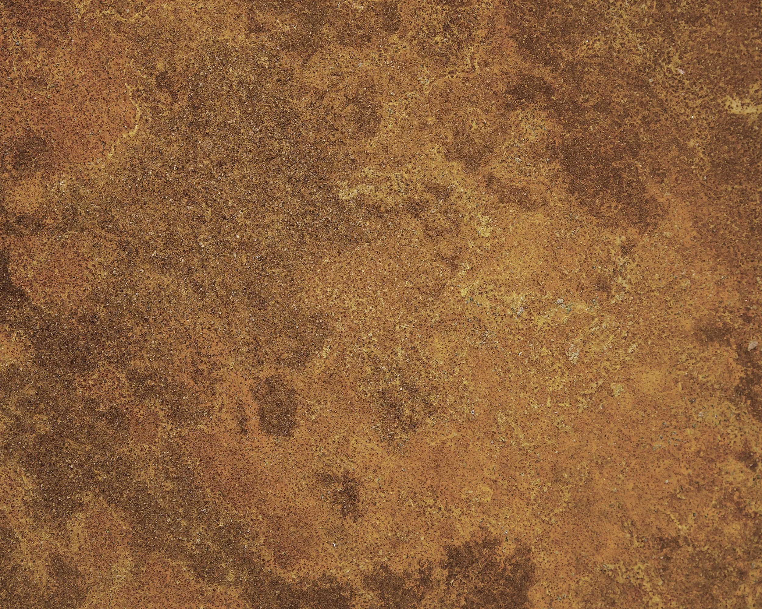Een close-up van een roestige metalen oppervlakte met een oranje tot bruin kleurenschaal en een korrelige textuur.