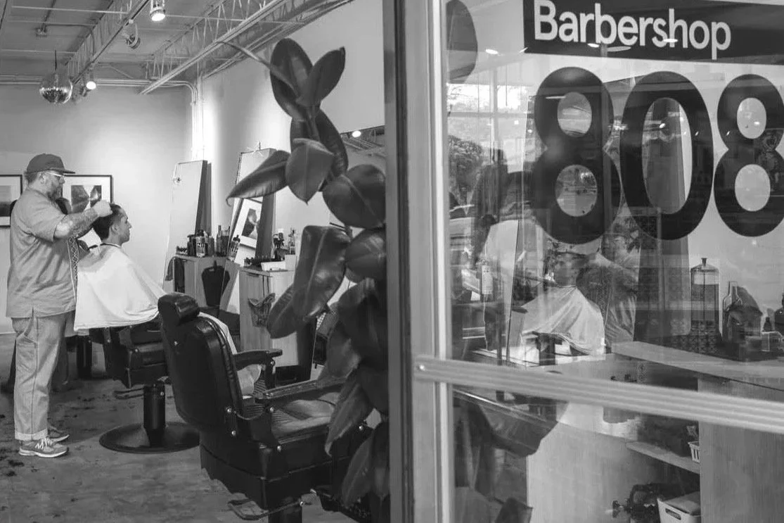 Inside a barbershop with a customer getting a haircut, a barber cutting hair. Scissor classic cut