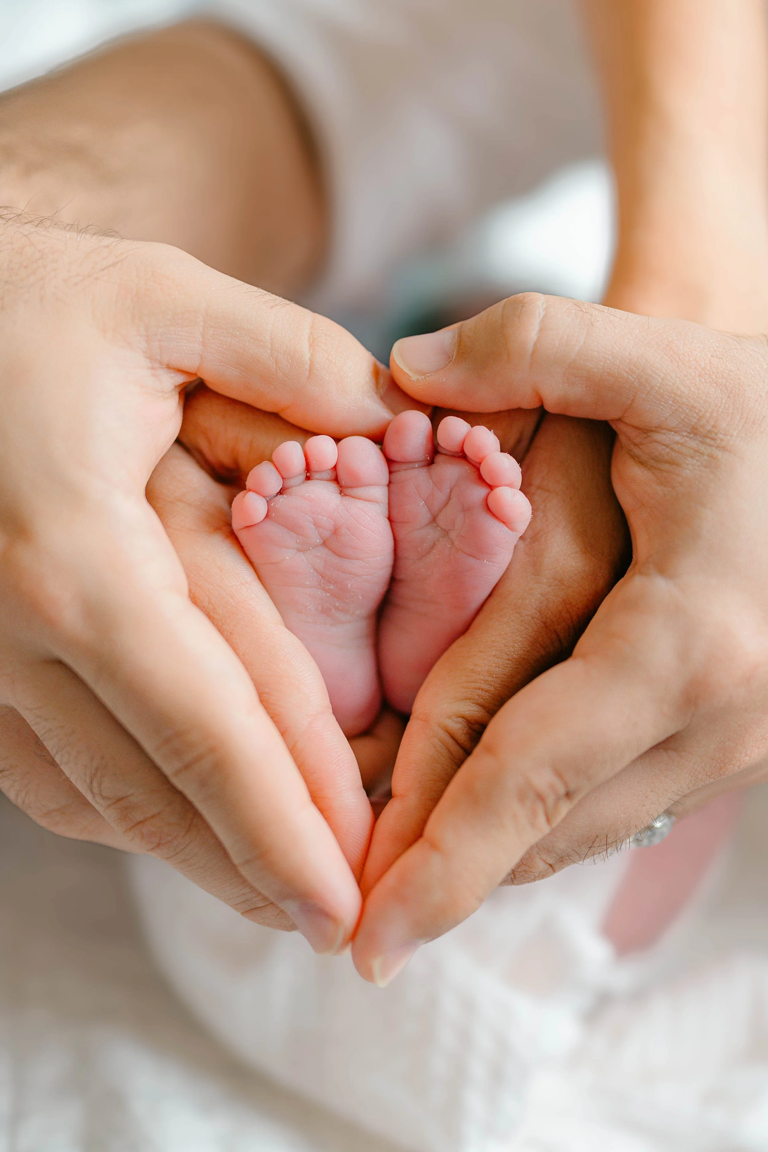 Parents’ hands surrounding their newborn baby’s tiny feet