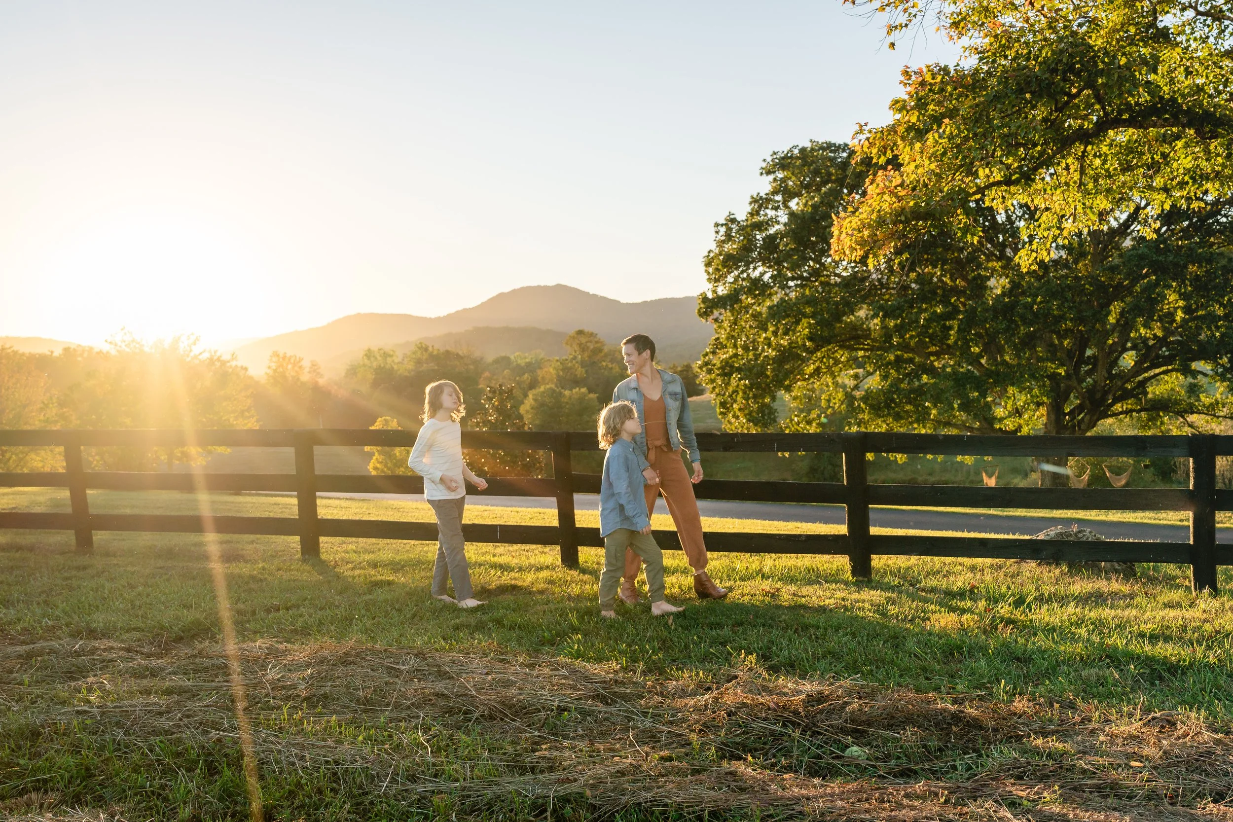  Mother and sons walking near a fence in warm golden-hour light with the Virginia countryside in the background. 