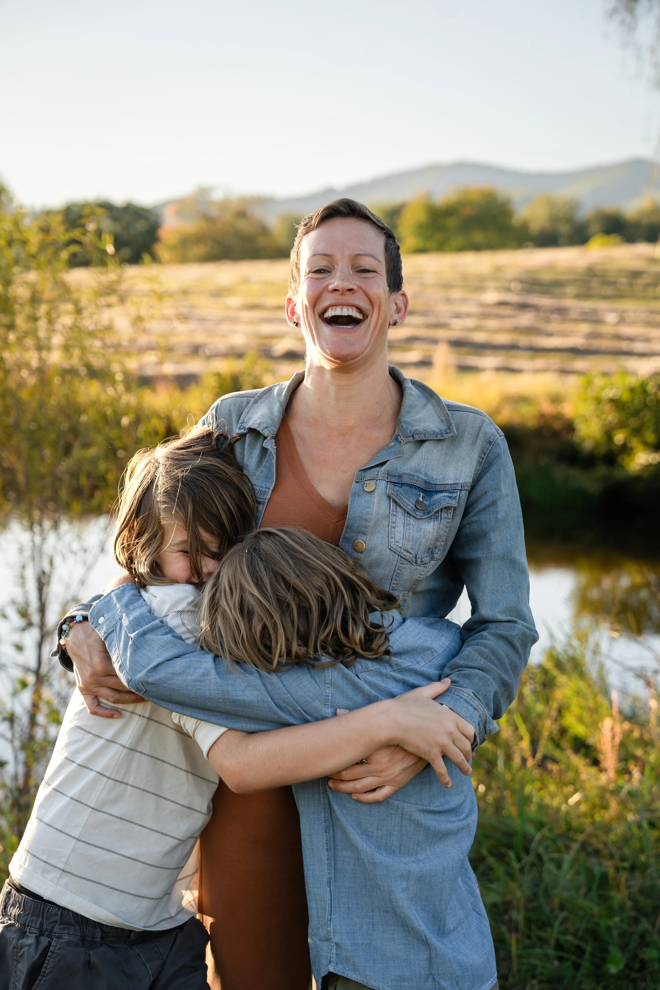  Mother laughing as her two sons hug her during a candid fall family photography session near Charlottesville. 