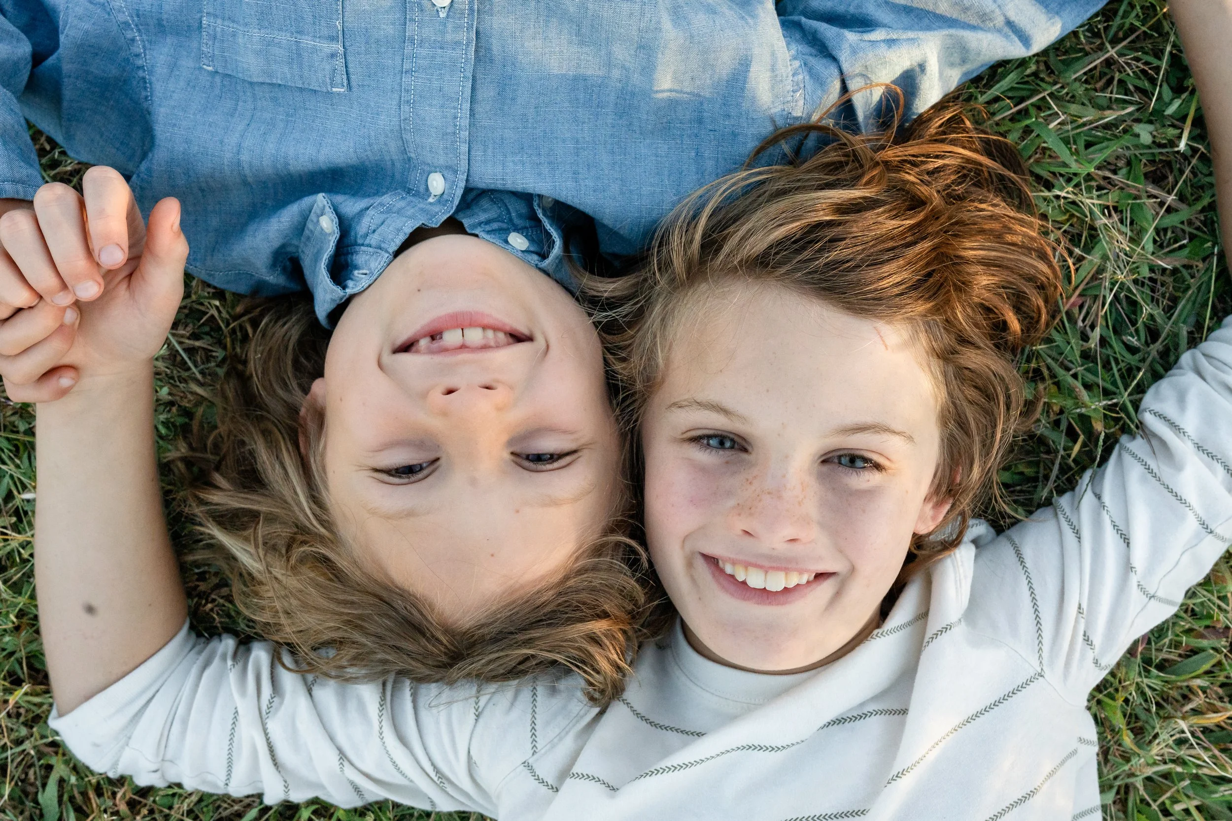  Two brothers lying together in the grass during a relaxed outdoor family photography session in Virginia. 
