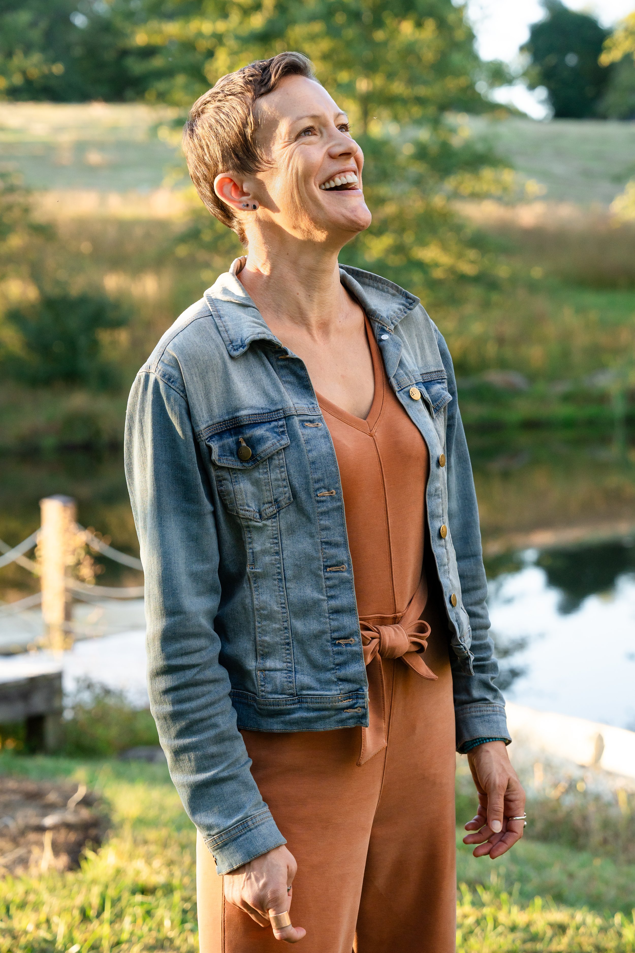  Candid portrait of a mother laughing outdoors in the soft autumn light during a family photography session. 