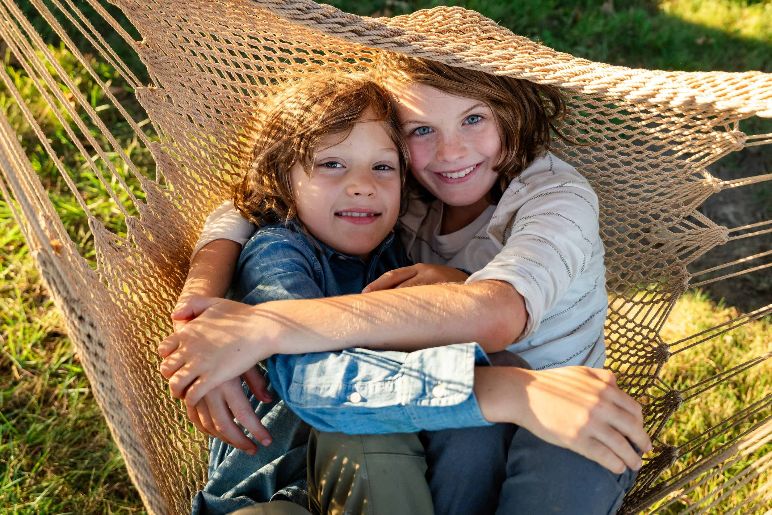  Two brothers relaxing together in a hammock during a playful fall family session at Grey Oaks Farm. 