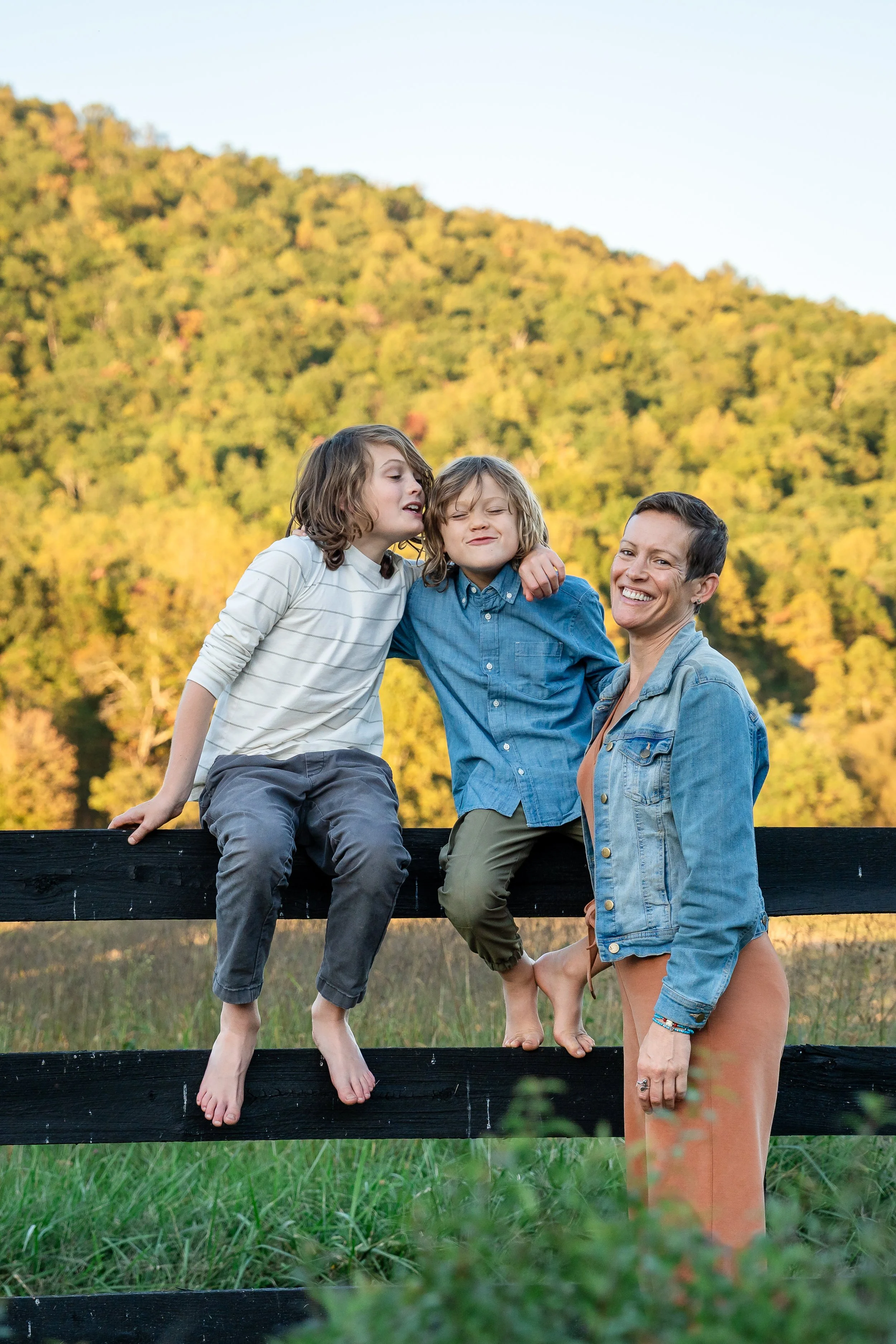  Mother posing with her two sons near a black fence with the Blue Ridge Mountains in the background. 