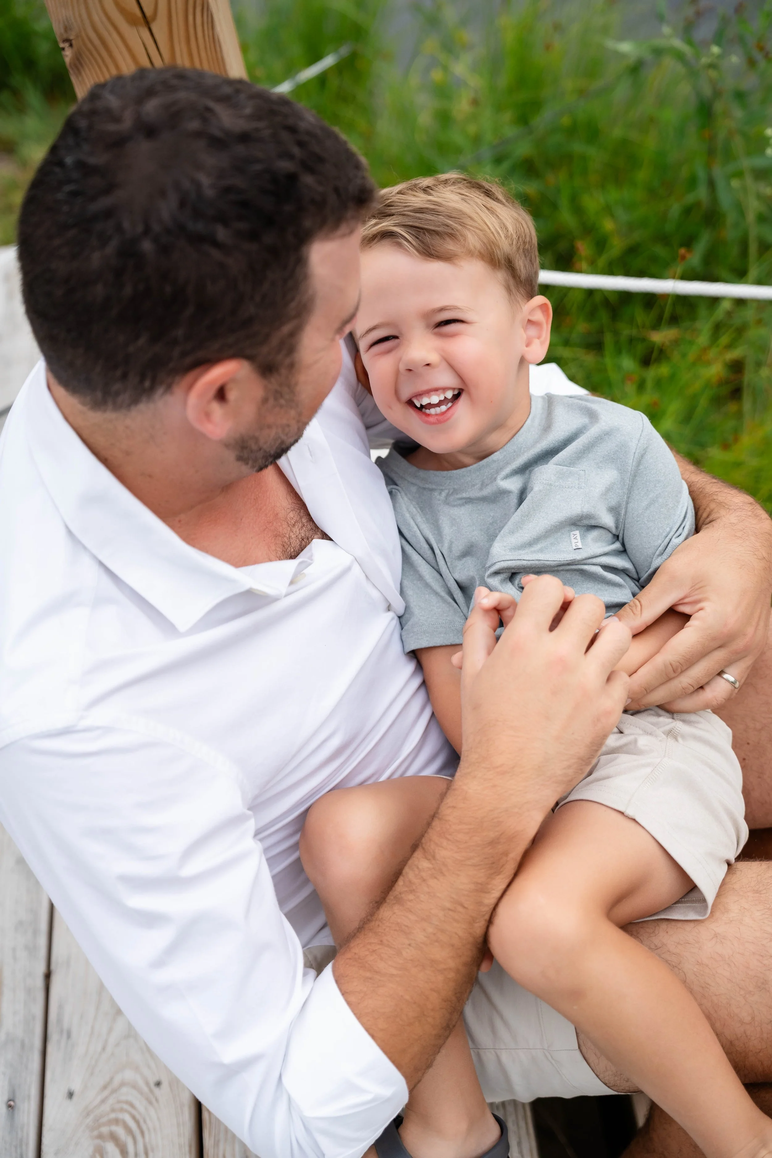  Father holding his laughing young son during a candid family photography session in Charlottesville, Virginia.   