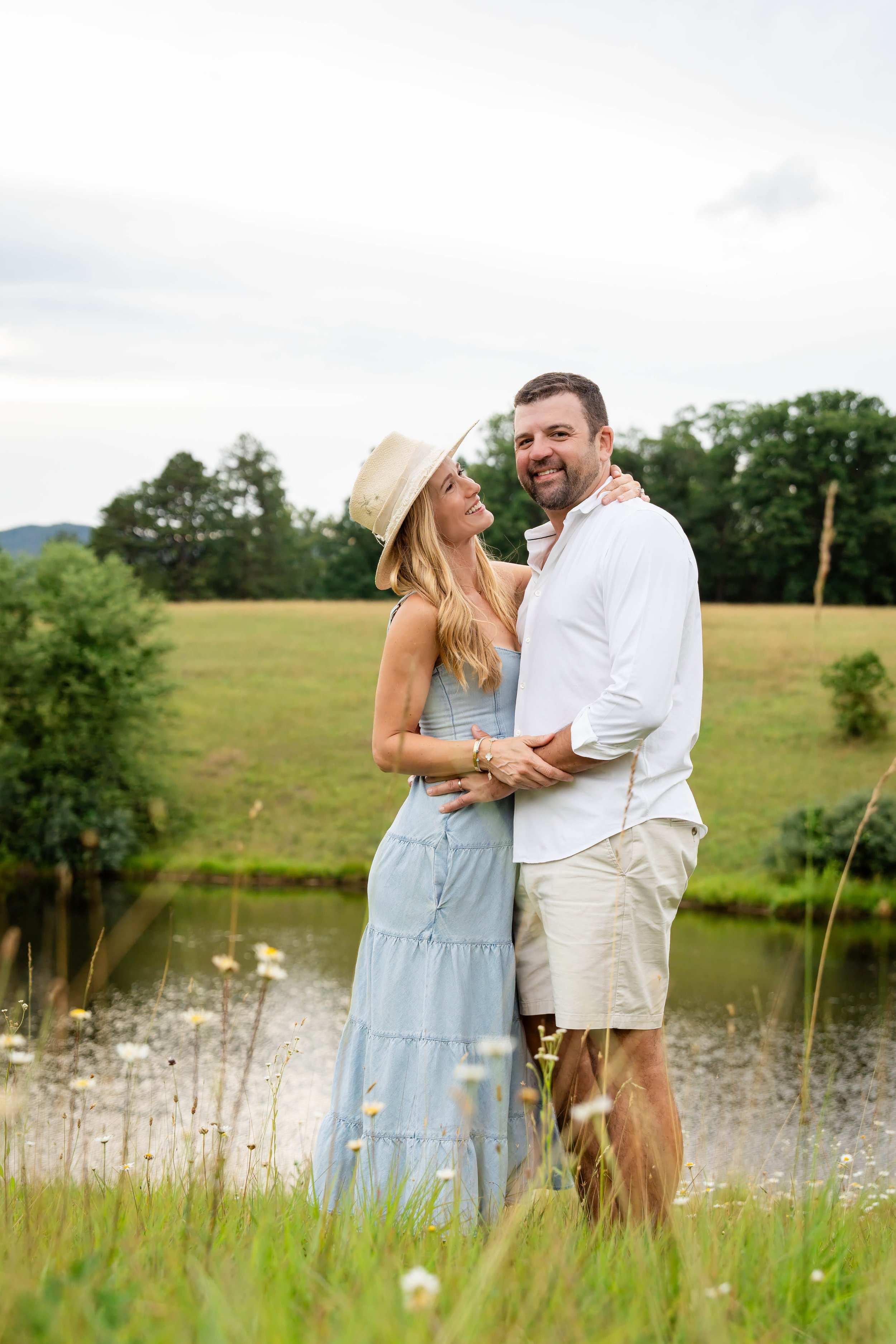  Parents embracing and smiling together beside the pond during their Charlottesville family photography session. 