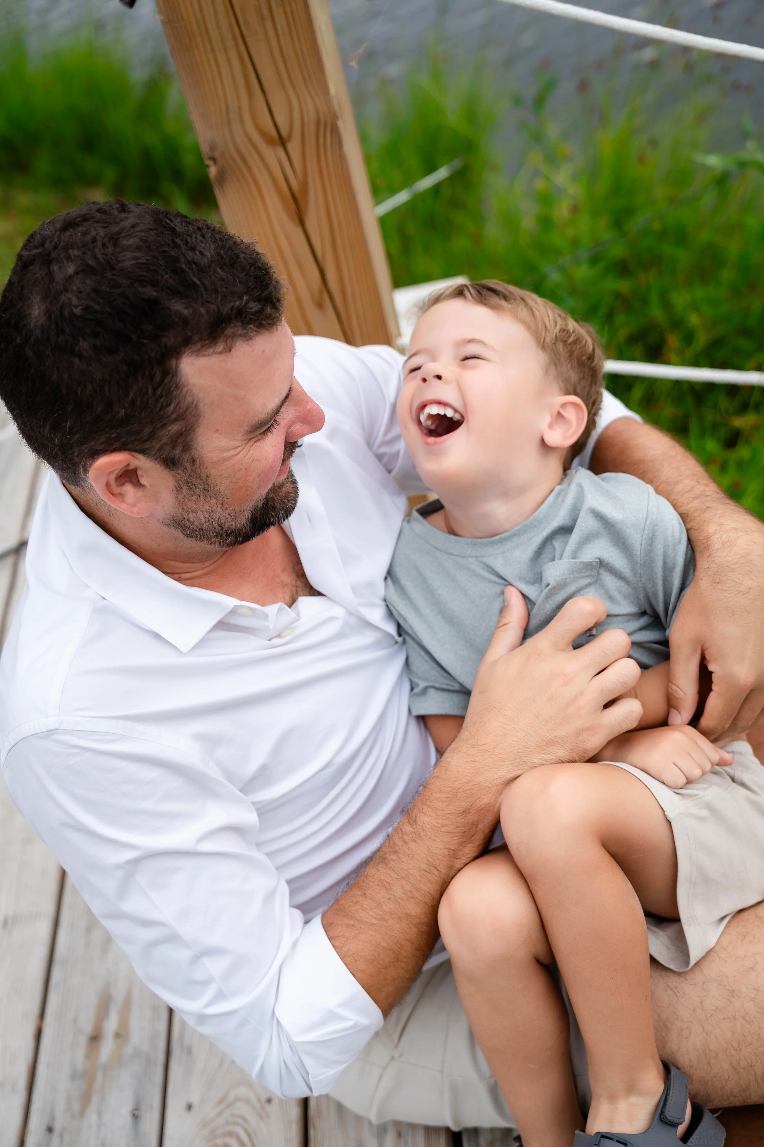 Father laughing joyfully with his young son during an outdoor family photography session