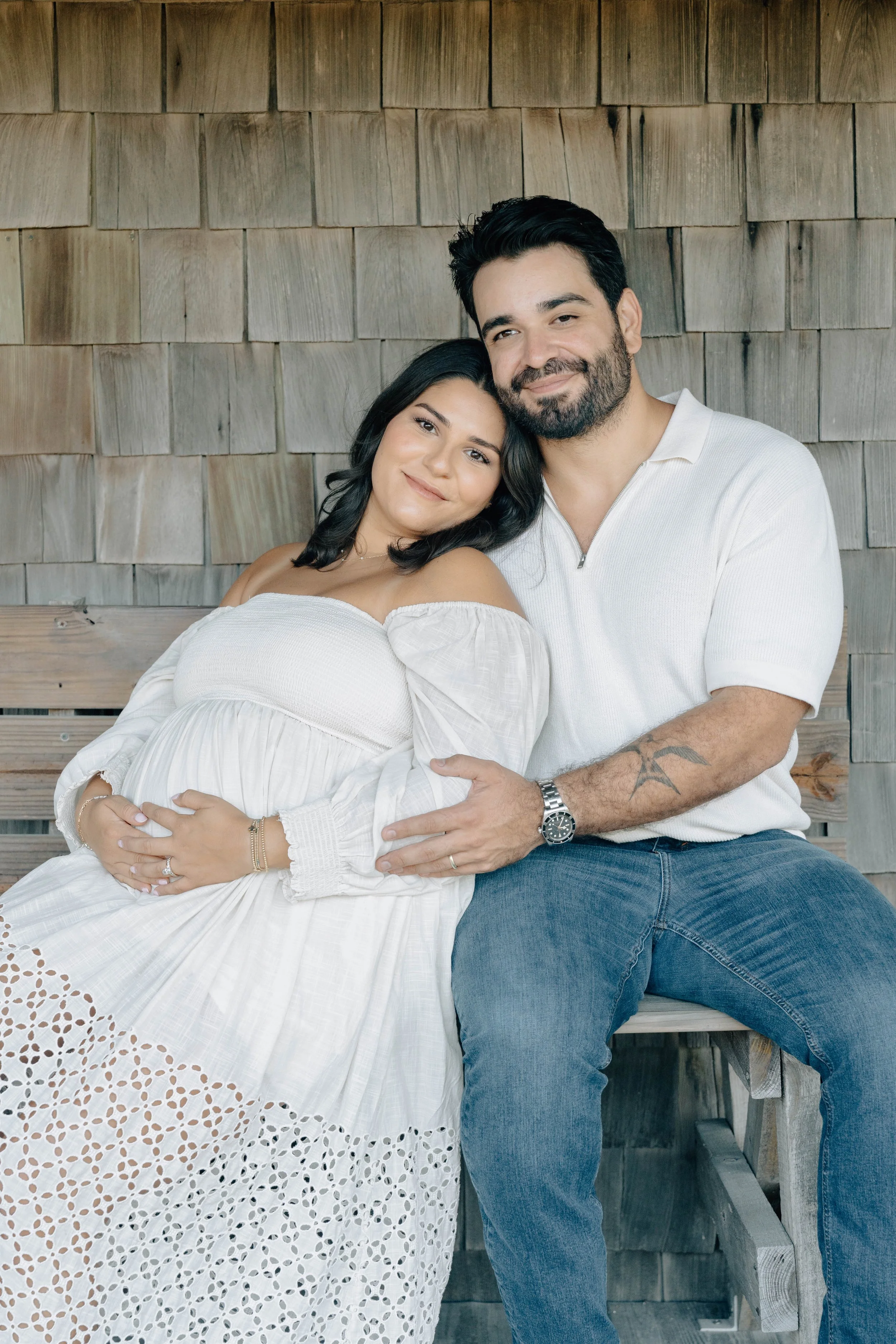 Expectant mother in a white dress with her partner during a maternity photography session