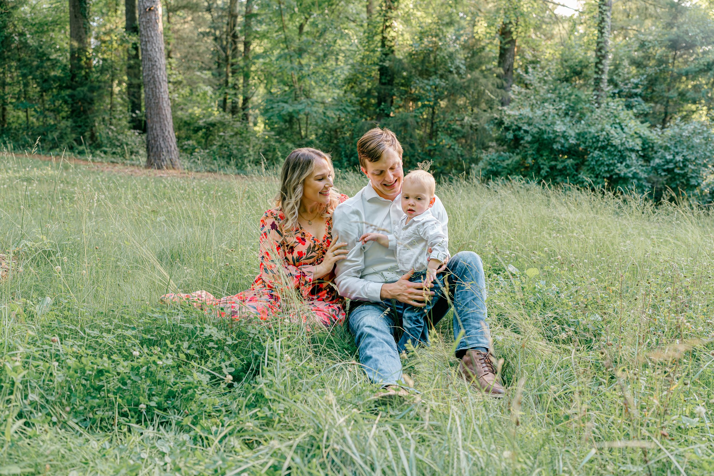 Family seated together in a sunny meadow during a Charlottesville, Virginia family session