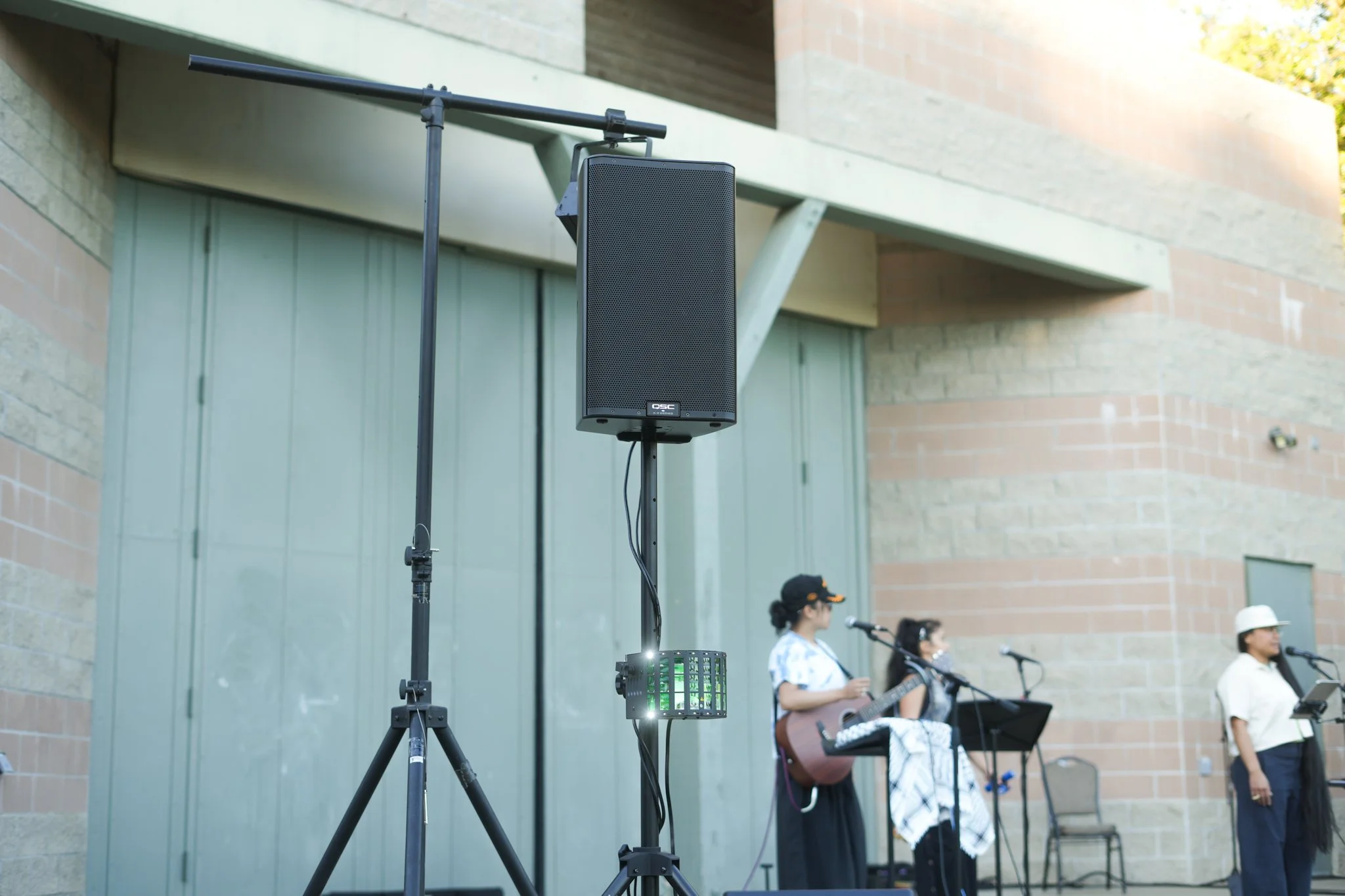 Professional PA speaker on a stand providing live sound reinforcement for an outdoor concert and community event in Sacramento.