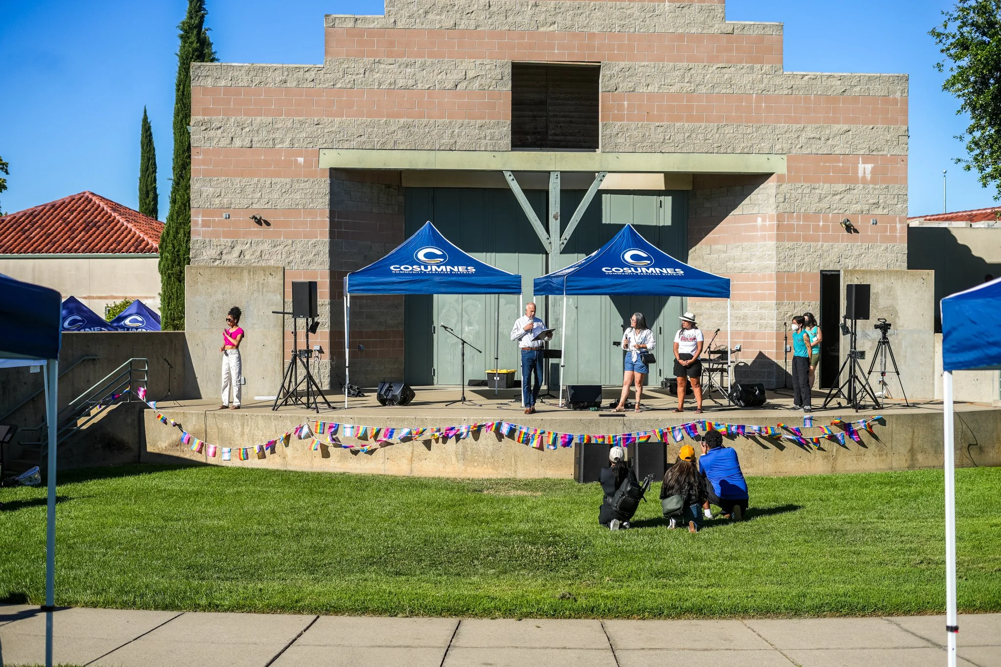 Wide view of a Sacramento community event featuring professional live sound rental, outdoor stage production, PA speakers, microphones, and audience coverage.