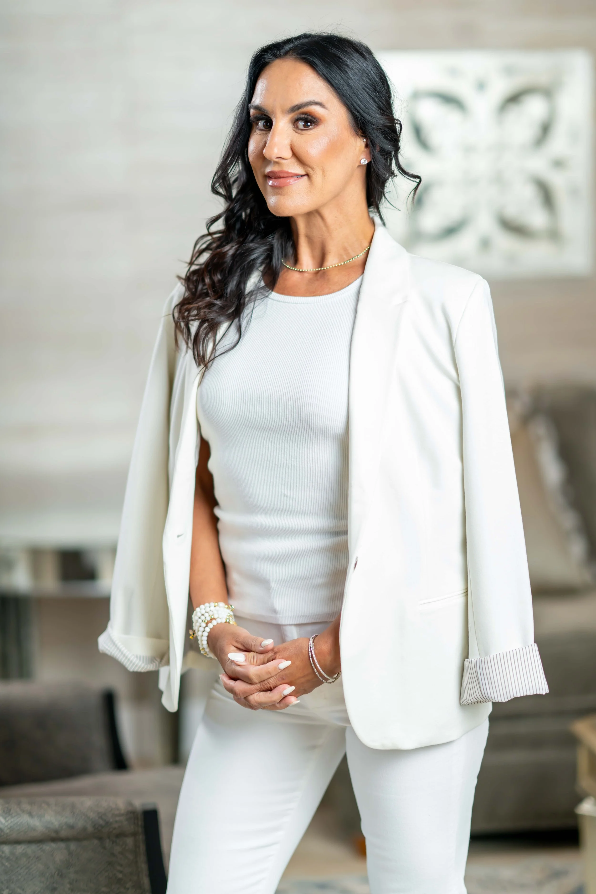 Sara Starkoff Green wearing a white blazer and pants, standing indoors smiling