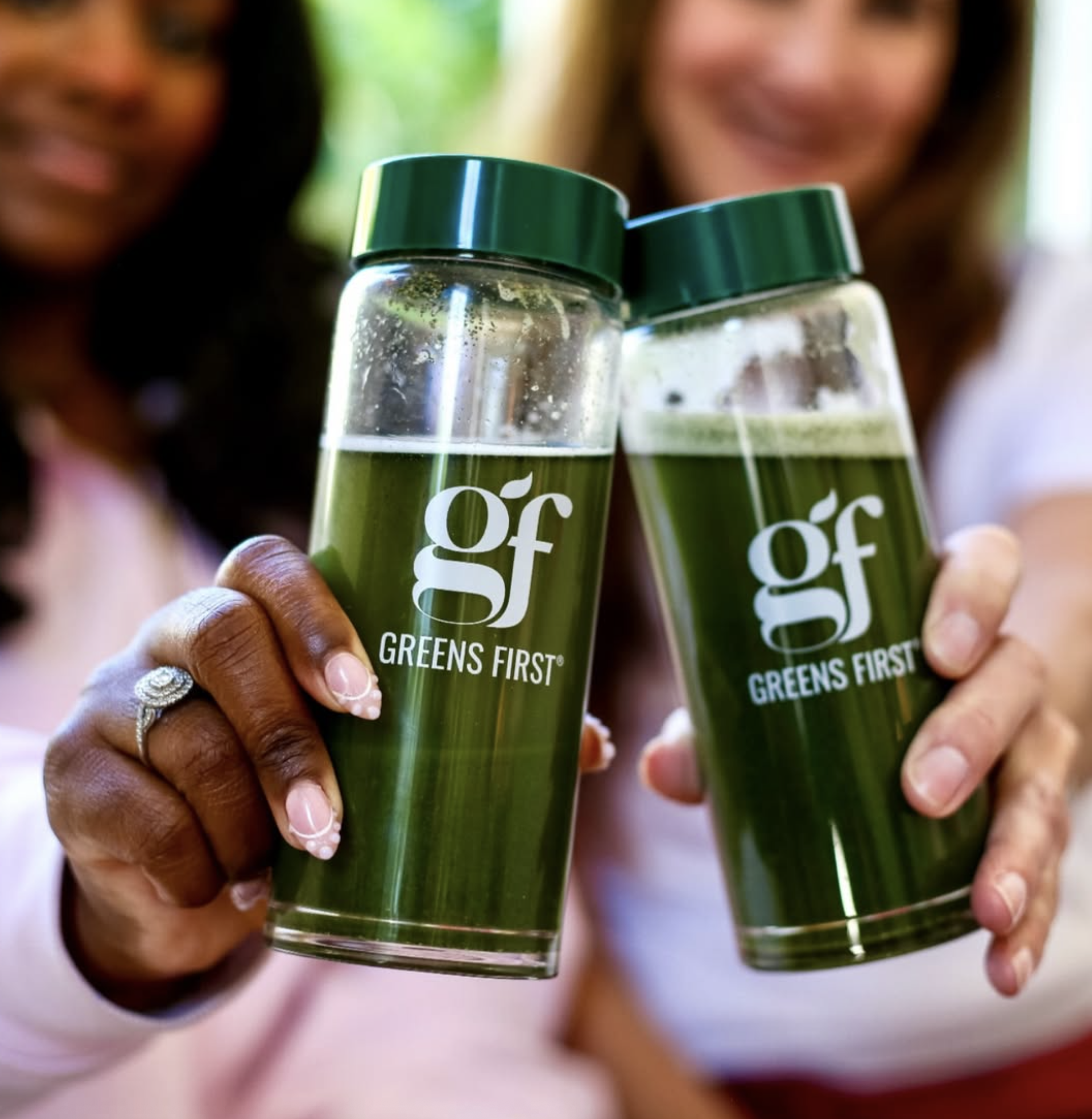 Person holding two bottles of green Greens First vegetable juice