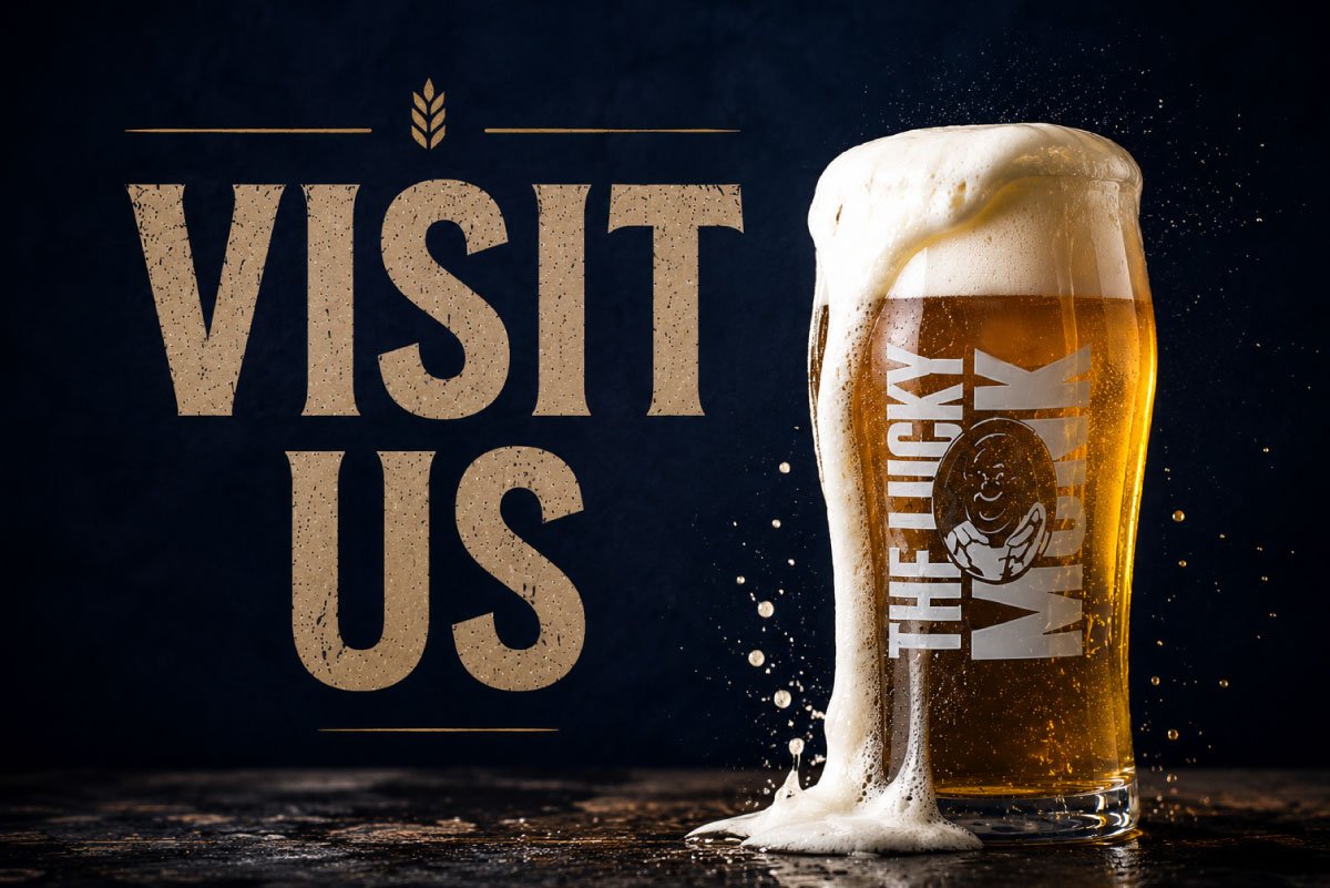 A pint glass of beer with foam overflowing, with a logo and text on the glass, next to the words "Visit Us" on a dark background.
