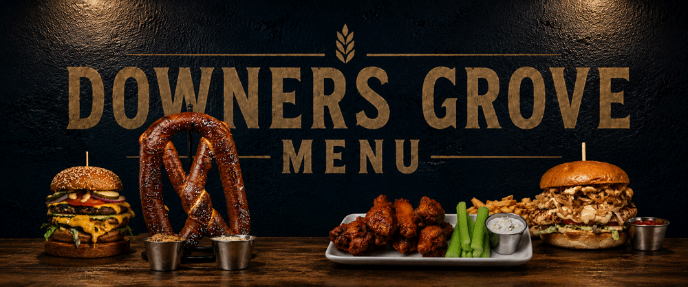 A menu display with a burger, pretzel with mustard, chicken wings with celery and ranch, and a pulled pork sandwich, against a black wall with the words "Downers Grove Menu".