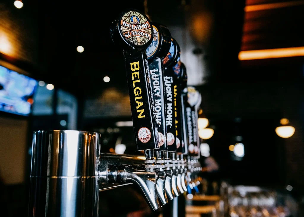 Beer taps in a bar with labels for different beers, including Belgian, Lucky Mountain, and FIFO.