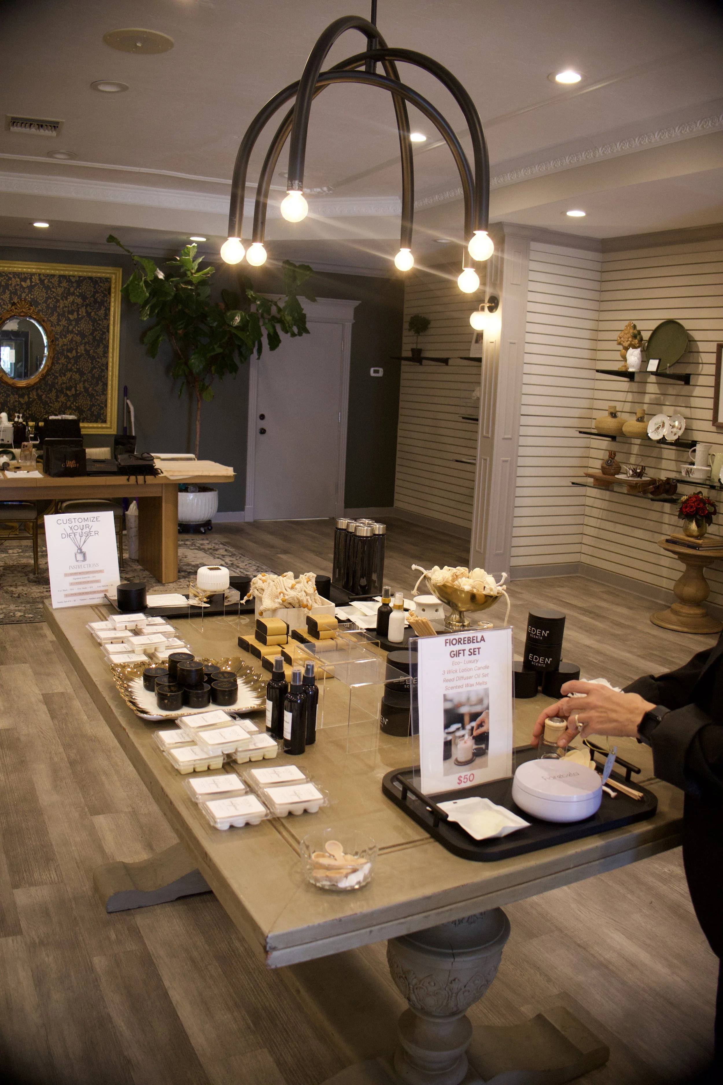 Display table with aromatic products, skincare items, and a sign for 'Fiorebela Gift Set' at an indoor boutique or gift shop.
