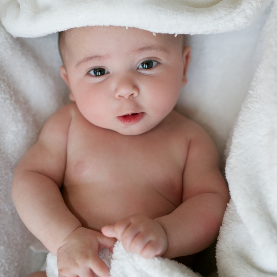 baby with brown eyes laying on a white towel
