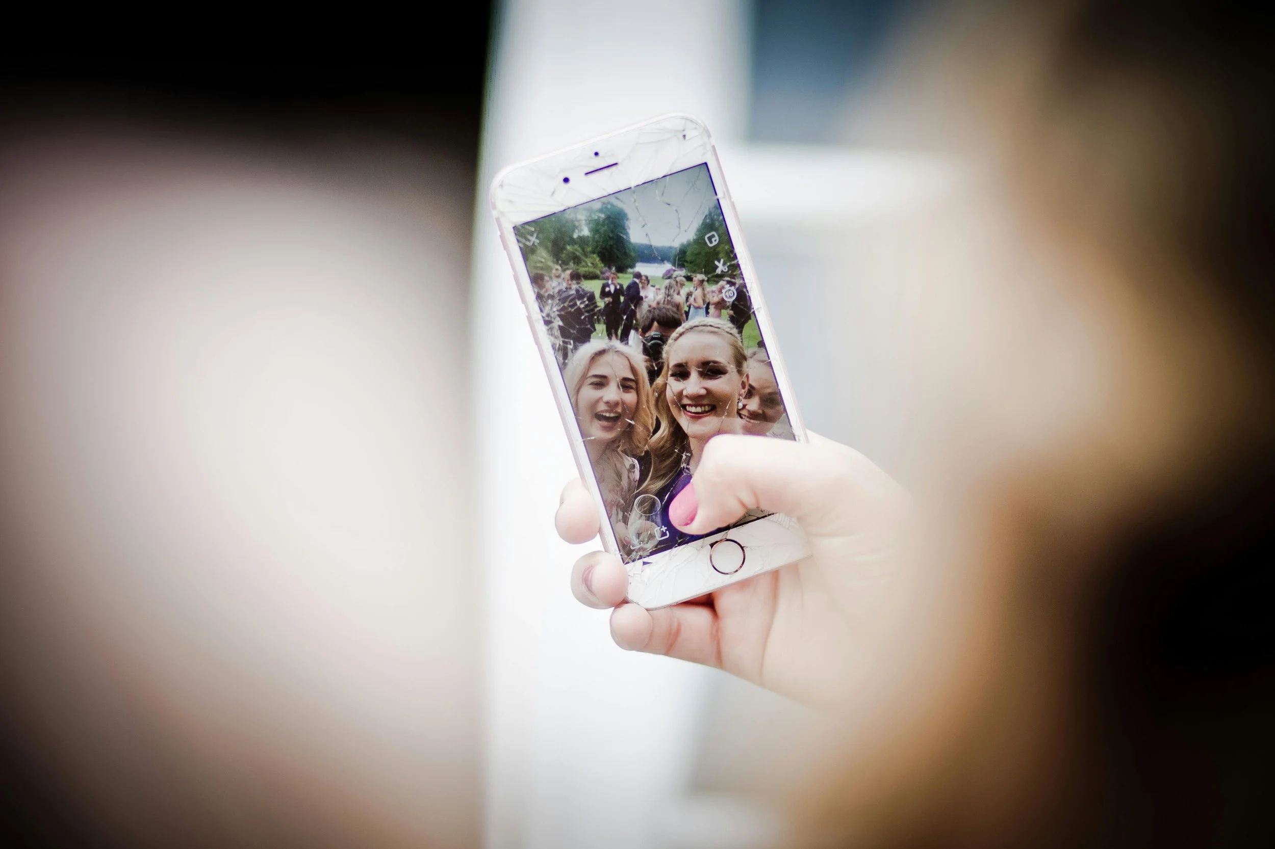A woman holding a phone showing a selfie with her friends, symbolizing shifting connection and communication in friendships after having a baby.
