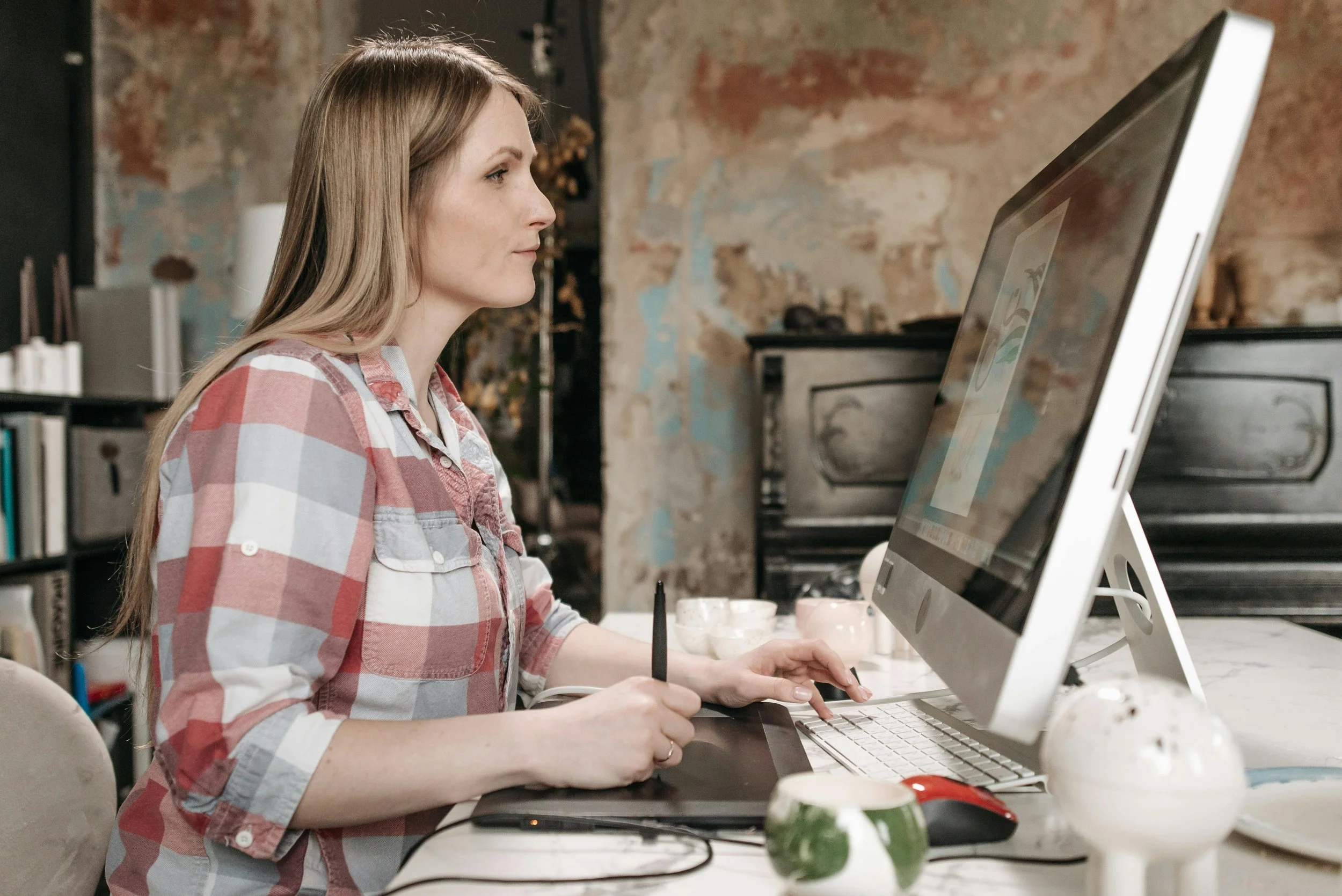 Woman working at a desktop computer with a design tablet, illustrating leadership in entrepreneurship and creative business work.