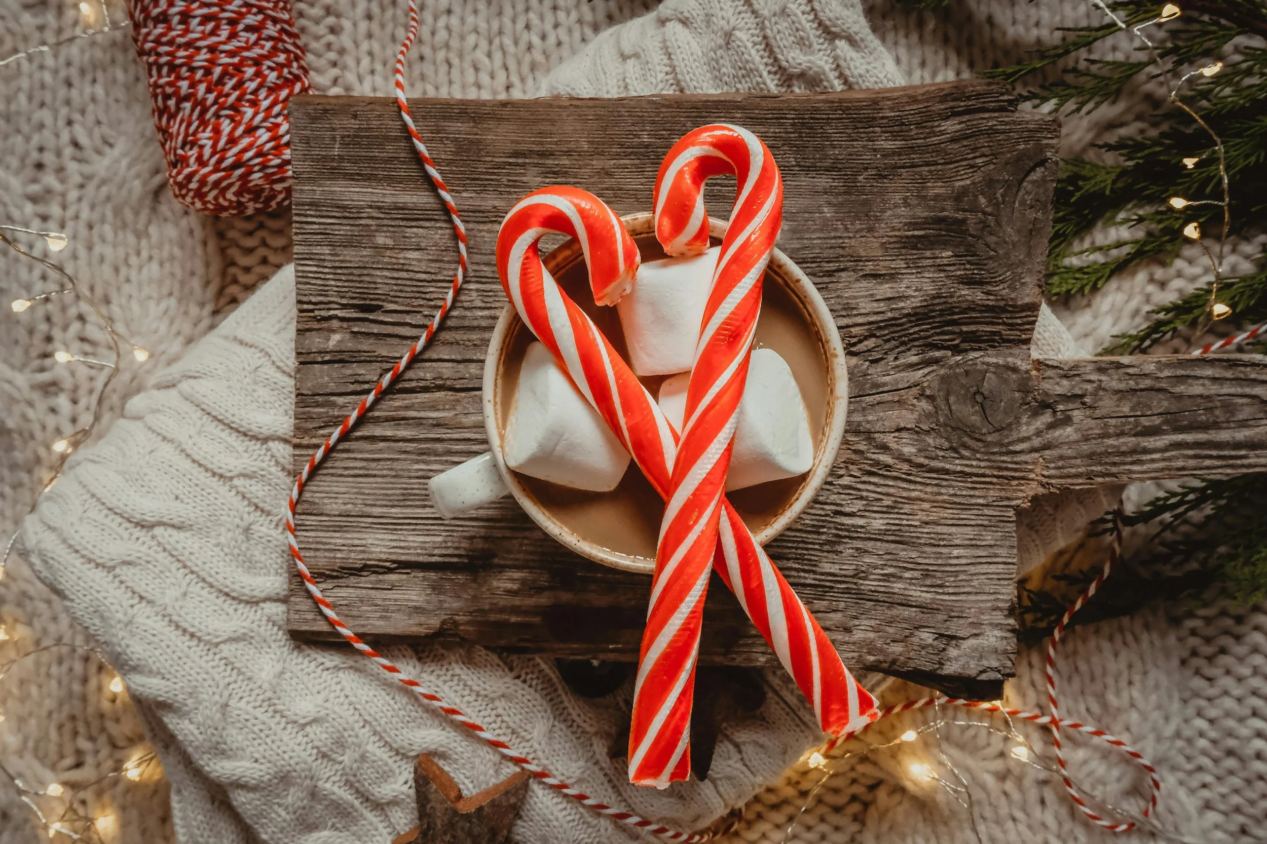 A cozy holiday scene with hot cocoa, marshmallows, and two candy canes forming a heart, symbolizing warmth and comfort for those who are single during the holidays.