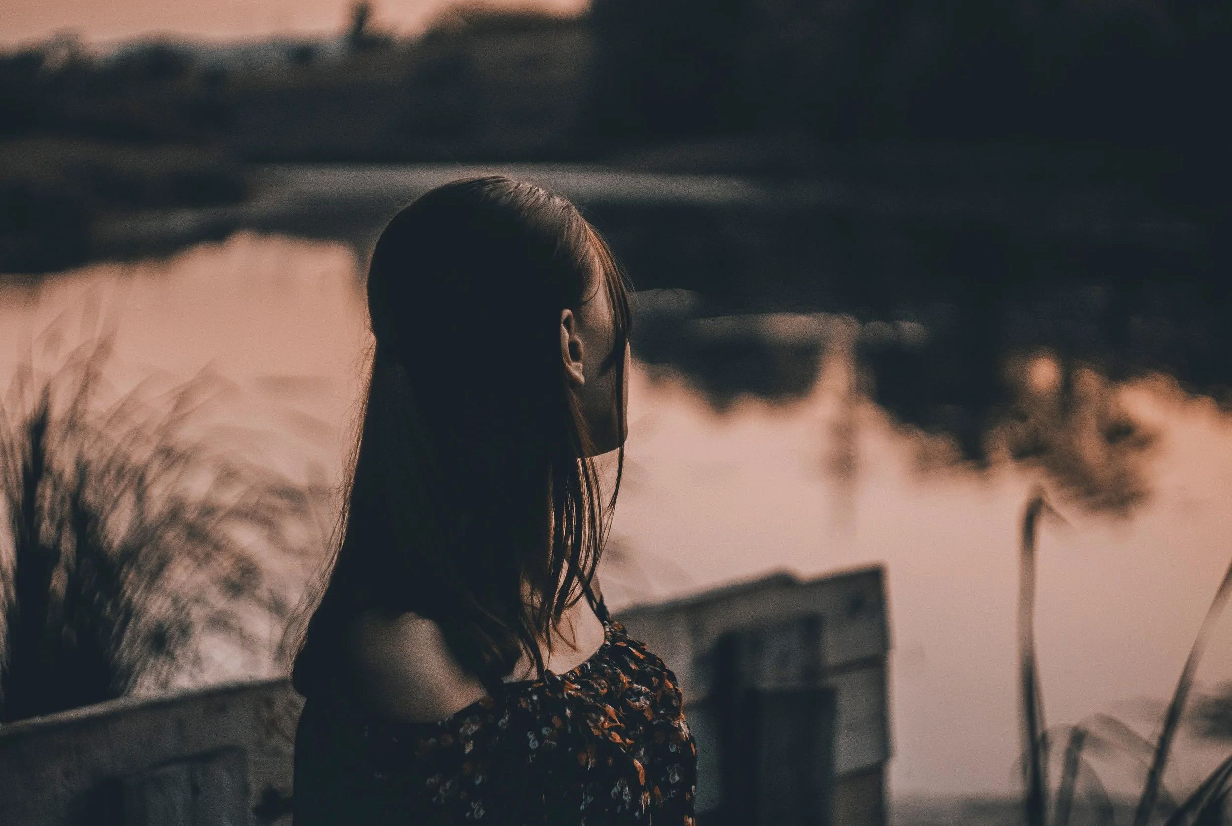 Woman sitting alone by a lake reflecting during an identity crisis after emotional healing and the transition out of survival mode.