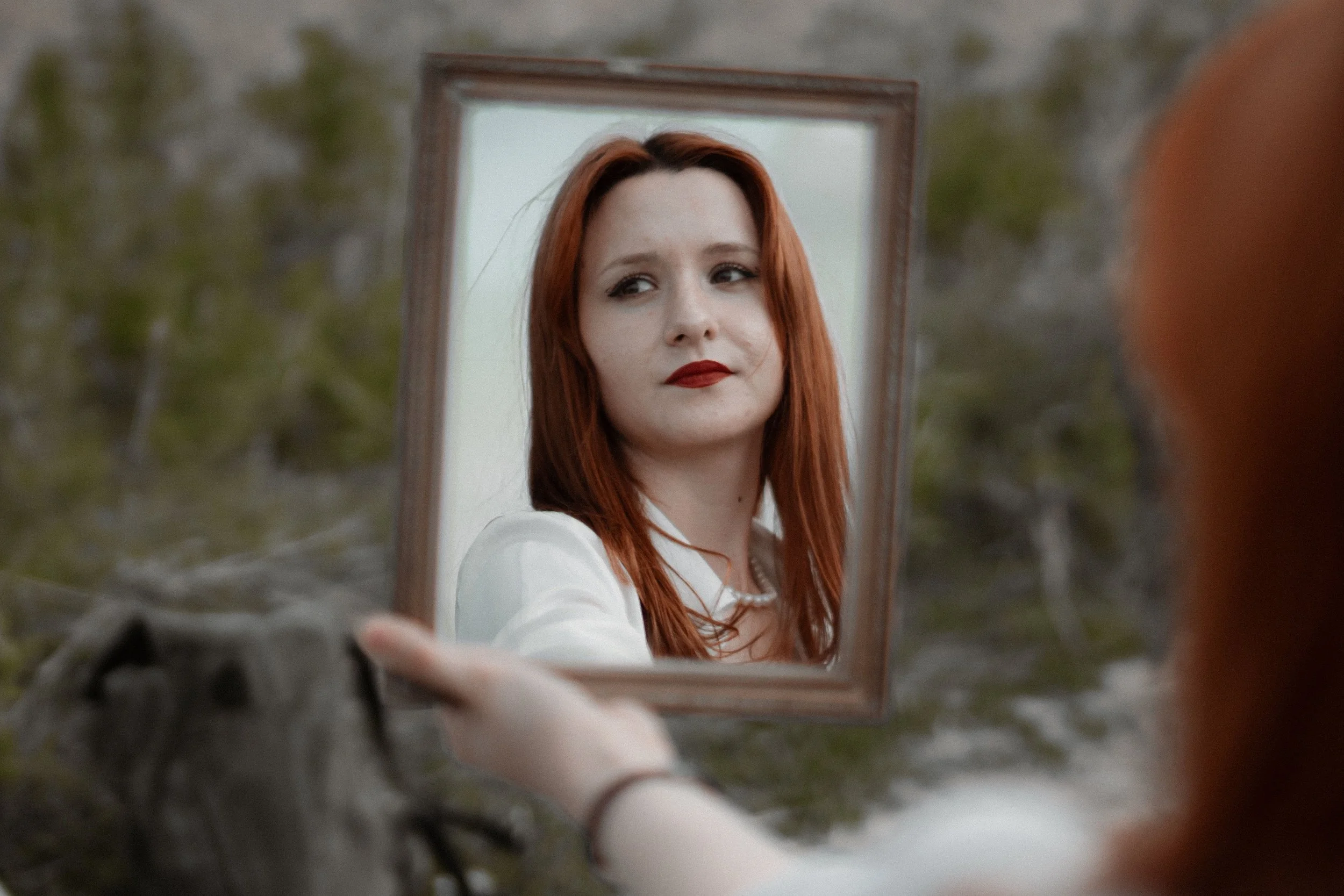 Woman looking at her reflection in a mirror, symbolizing the social rewards of hyper-independent women and the identity built around being strong, capable, and self-reliant.