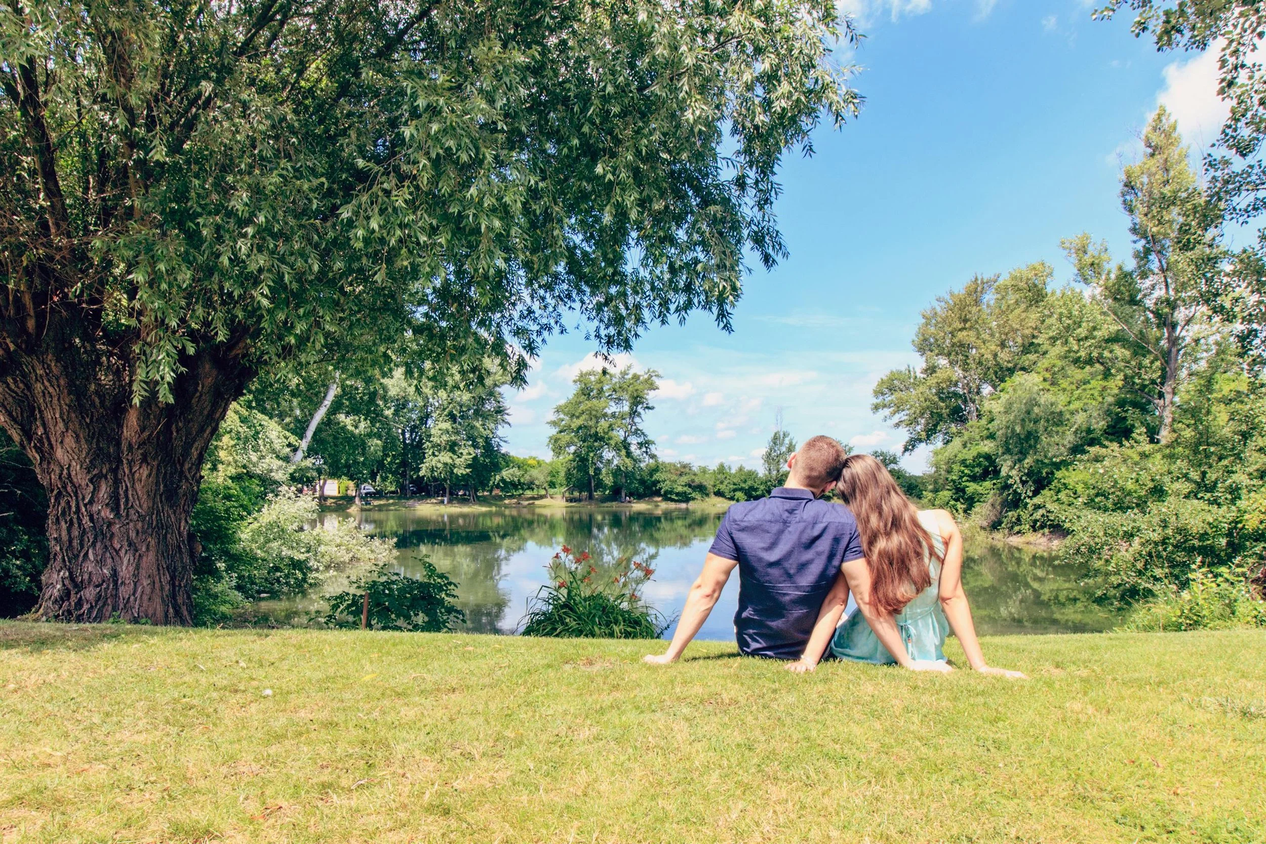 Couple sitting together by a lake in a park, representing disclosure and honest conversations about the future in dating.