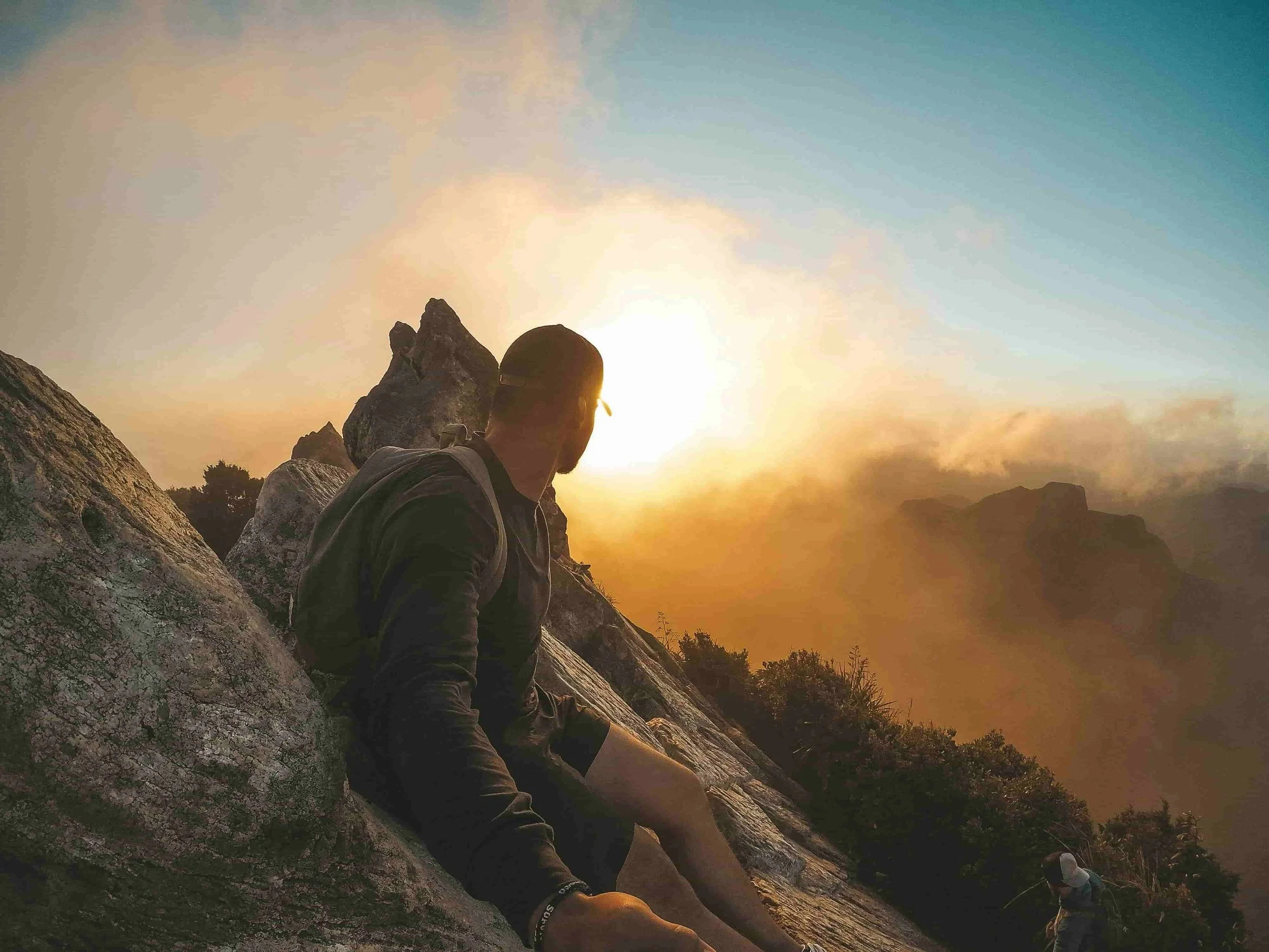 A man sitting on a mountain at sunrise, symbolizing self-reflection, emotional healing, and personal growth through individual therapy.